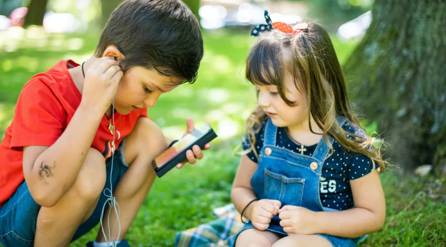 Bambini all’aperto che utilizzano uno smartphone, esempio di dipendenza tecnologica nei bambini