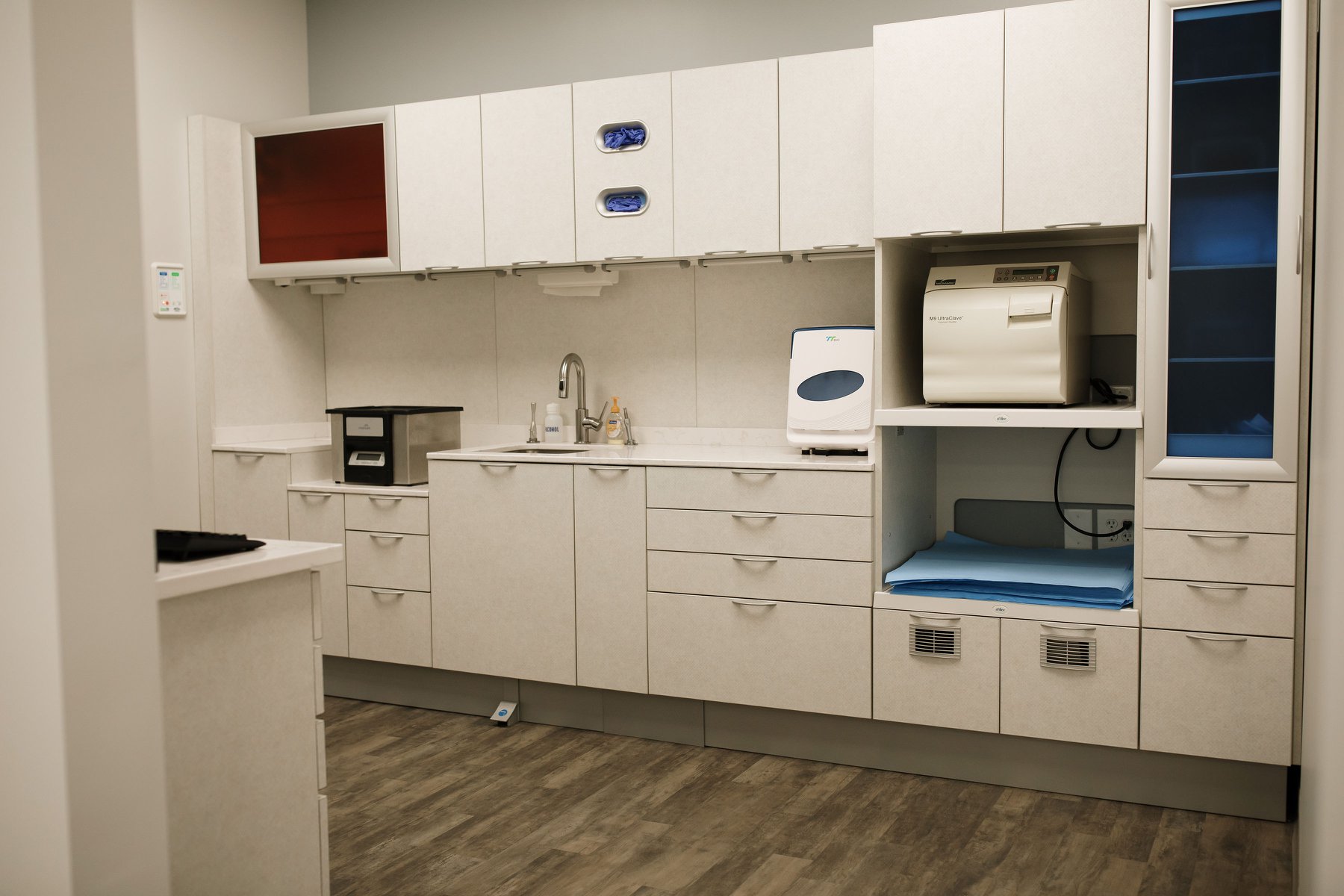 Modern lab with white cabinetry, a blue accent, and appliances, featuring a clean, organized layout.