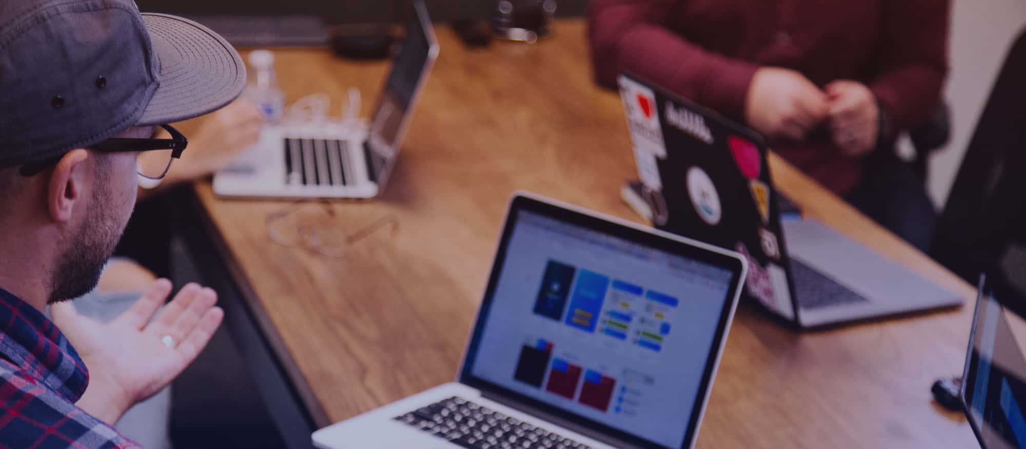 A few people sitting in a meeting with their laptops