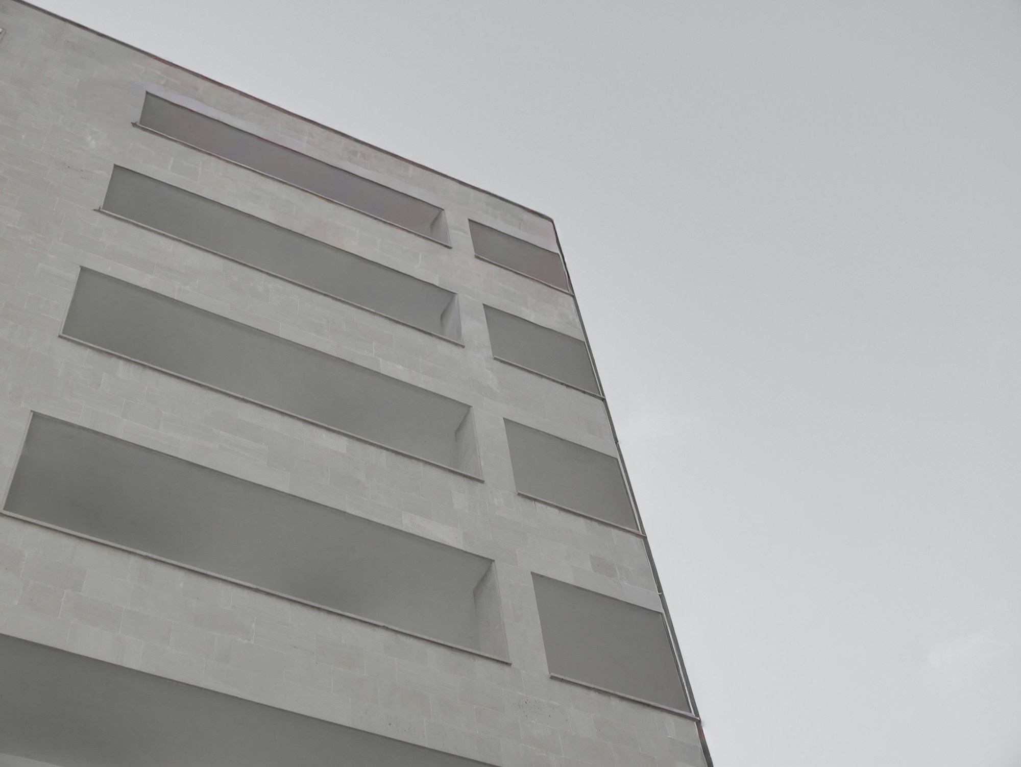 Stone facade of the Zuxen studio building with recessed window bands