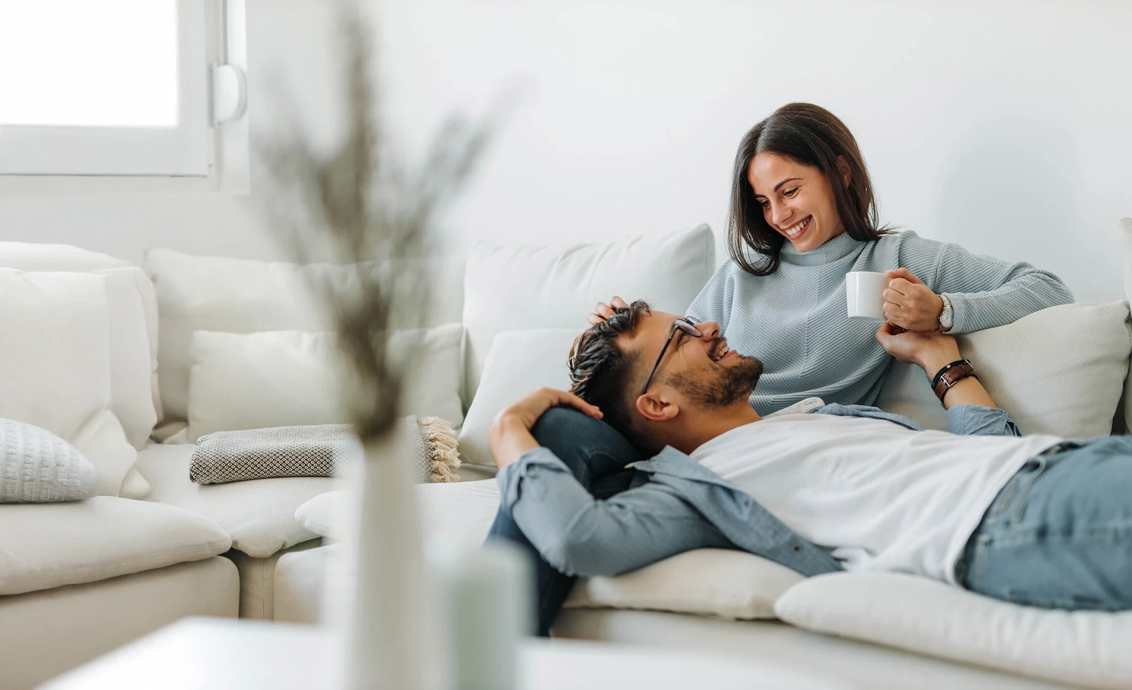 Woman smiling and her partner sitting on the couch representing Flouria’s fertility care
