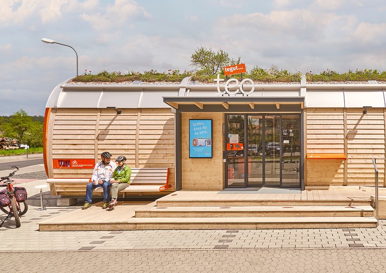 Frontansicht des tegut… teo in Rasdorf mit Kund:innen – nachhaltiges Micro-Store Konzept gestaltet von Design for Human Nature in Hamburg.