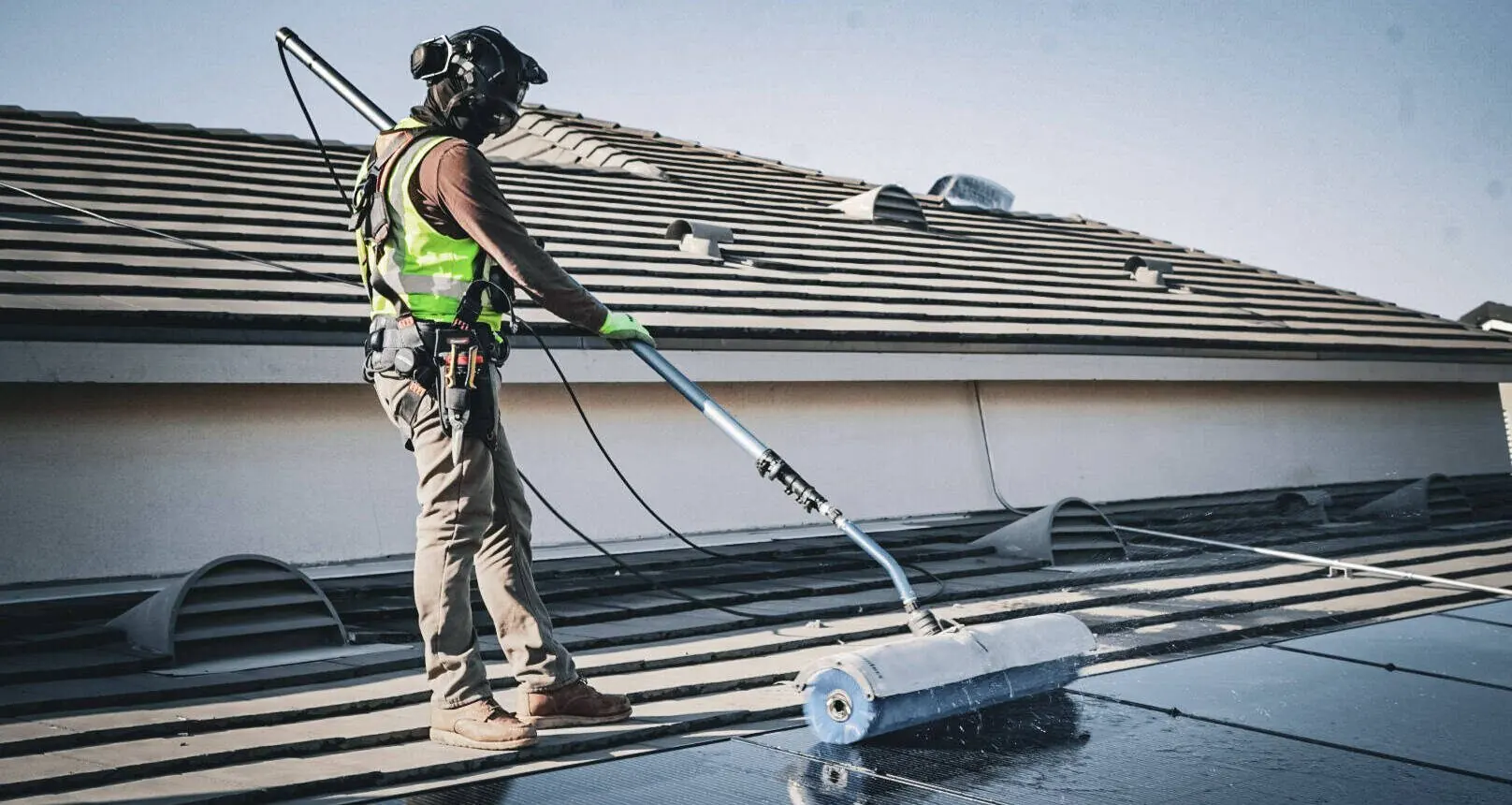 Technician in hi-vis cleaning tile-roof solar panels with a pole brush | Premier Solar Service, serving Central Valley, CA