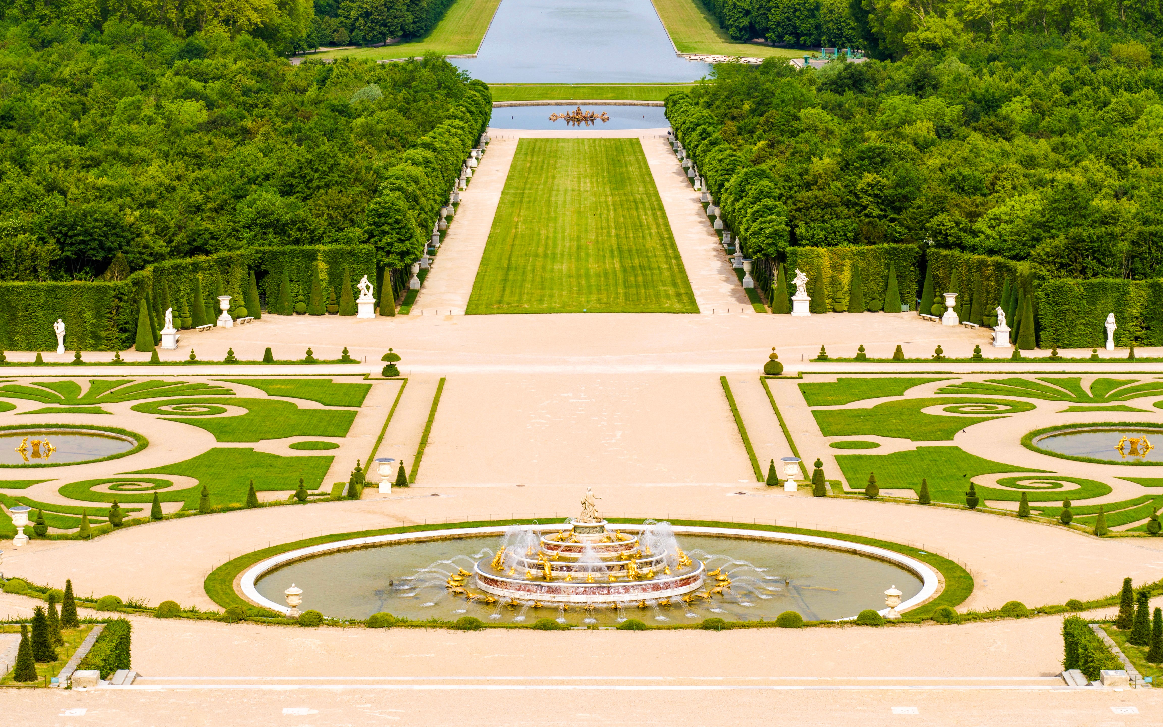 巴黎凡尔赛宫的喷泉和花园，修剪整齐的草坪以及雕像。