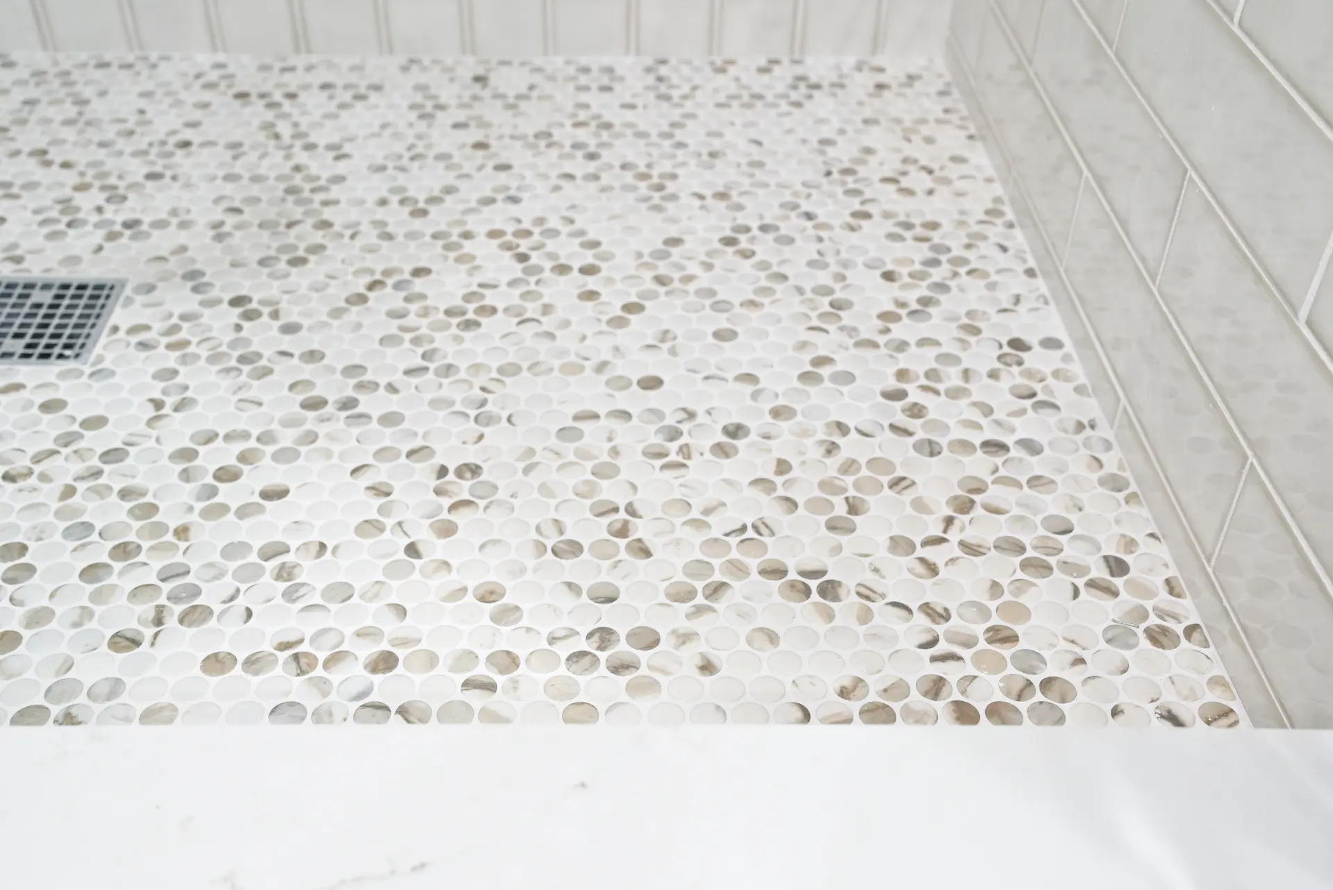 Close-up of the Jack and Jill bathroom's shower pan tile, showcasing the intricate tile work and quality materials that add a touch of sophistication in the Dana Point Full Remodel. Photo by Todd Huge.