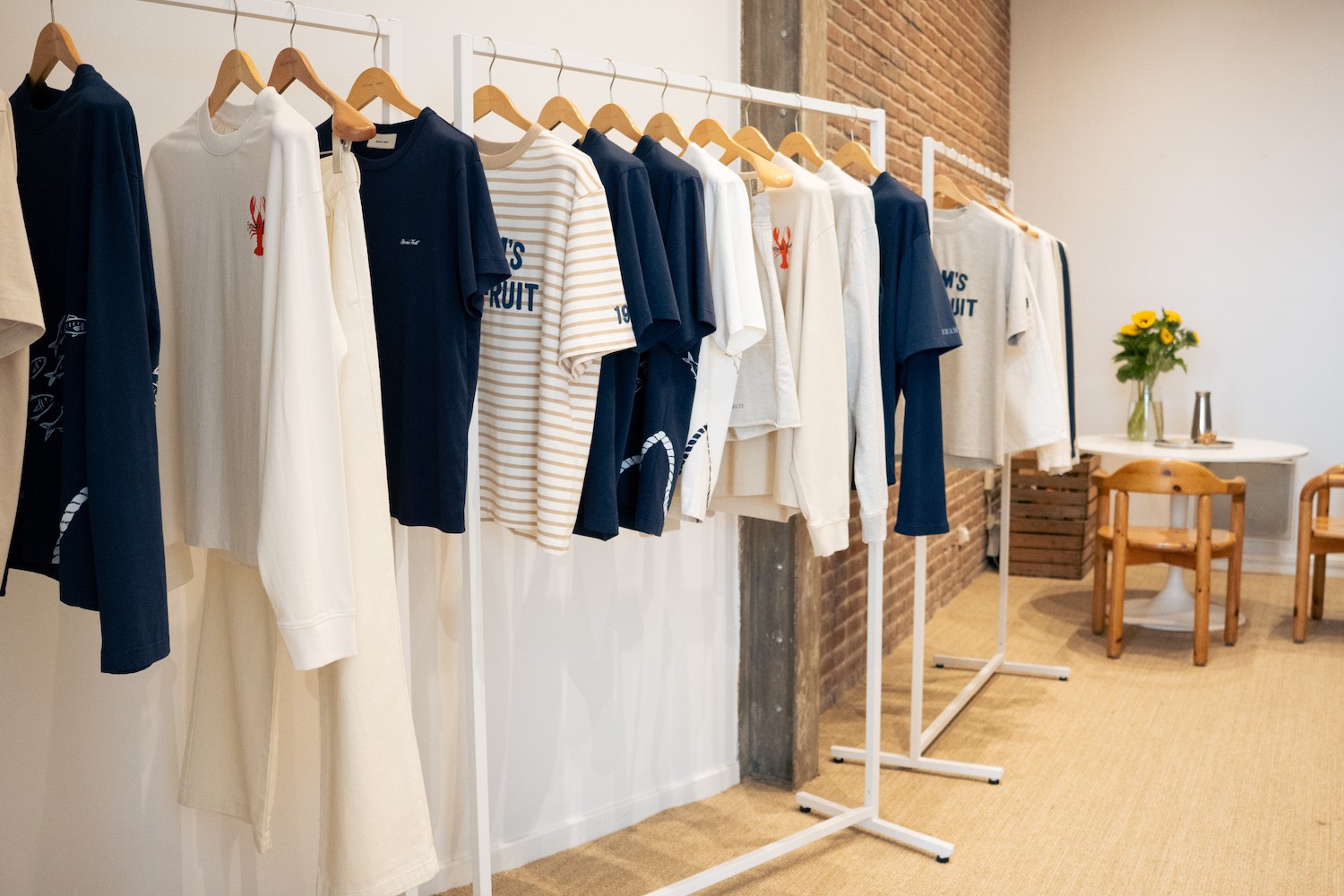 Plusieurs portants avec une collection de t-shirts d'été beiges, blancs et marines