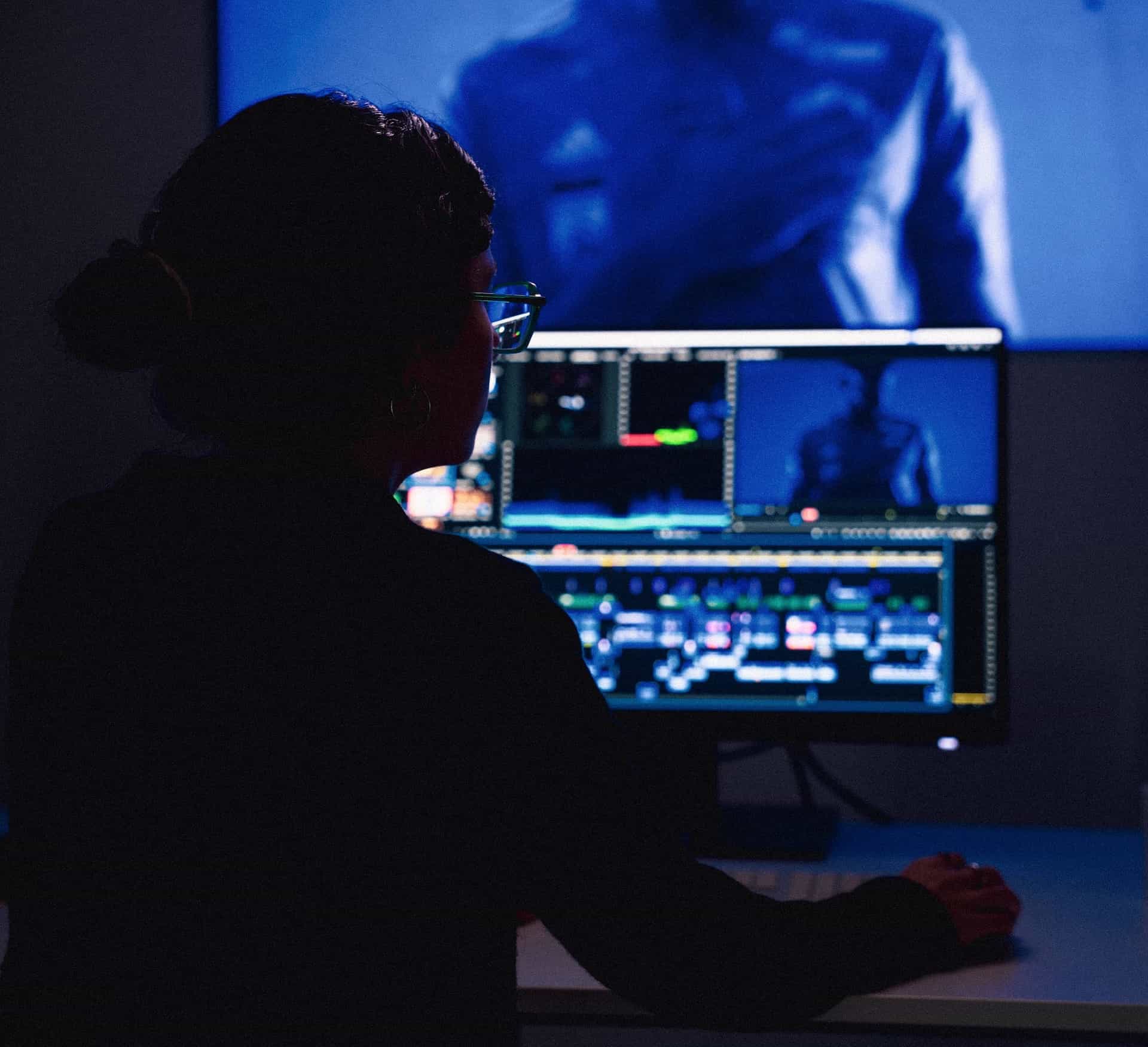 Eine Frau vor einer Videoschnitt-Timeline in einer dunklen Umgebung