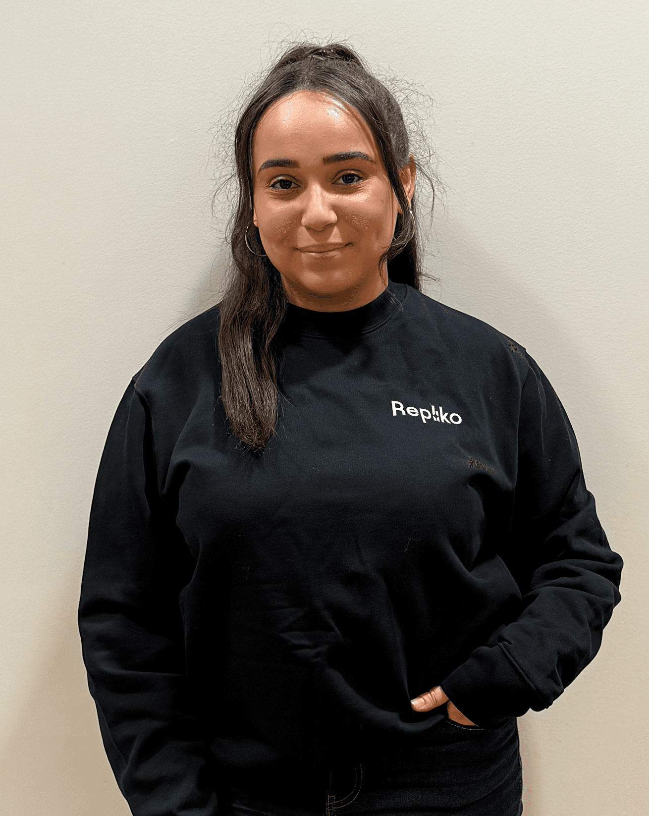 A young man with dark hair smiles at the camera, set against a modern indoor background.