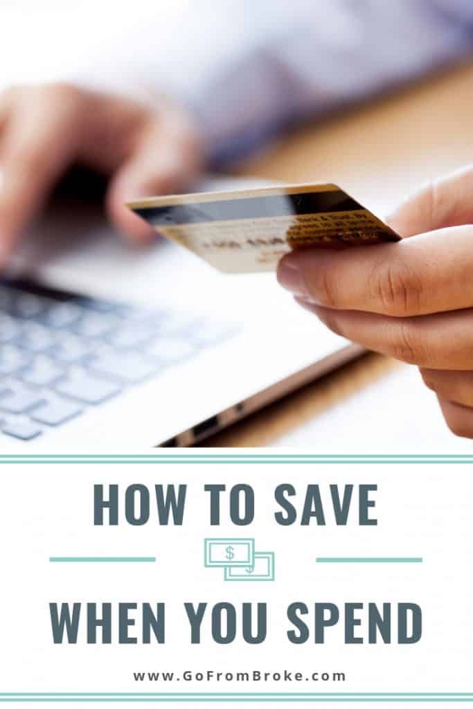 Close-up of one hand holding a credit card while the other types on a laptop.