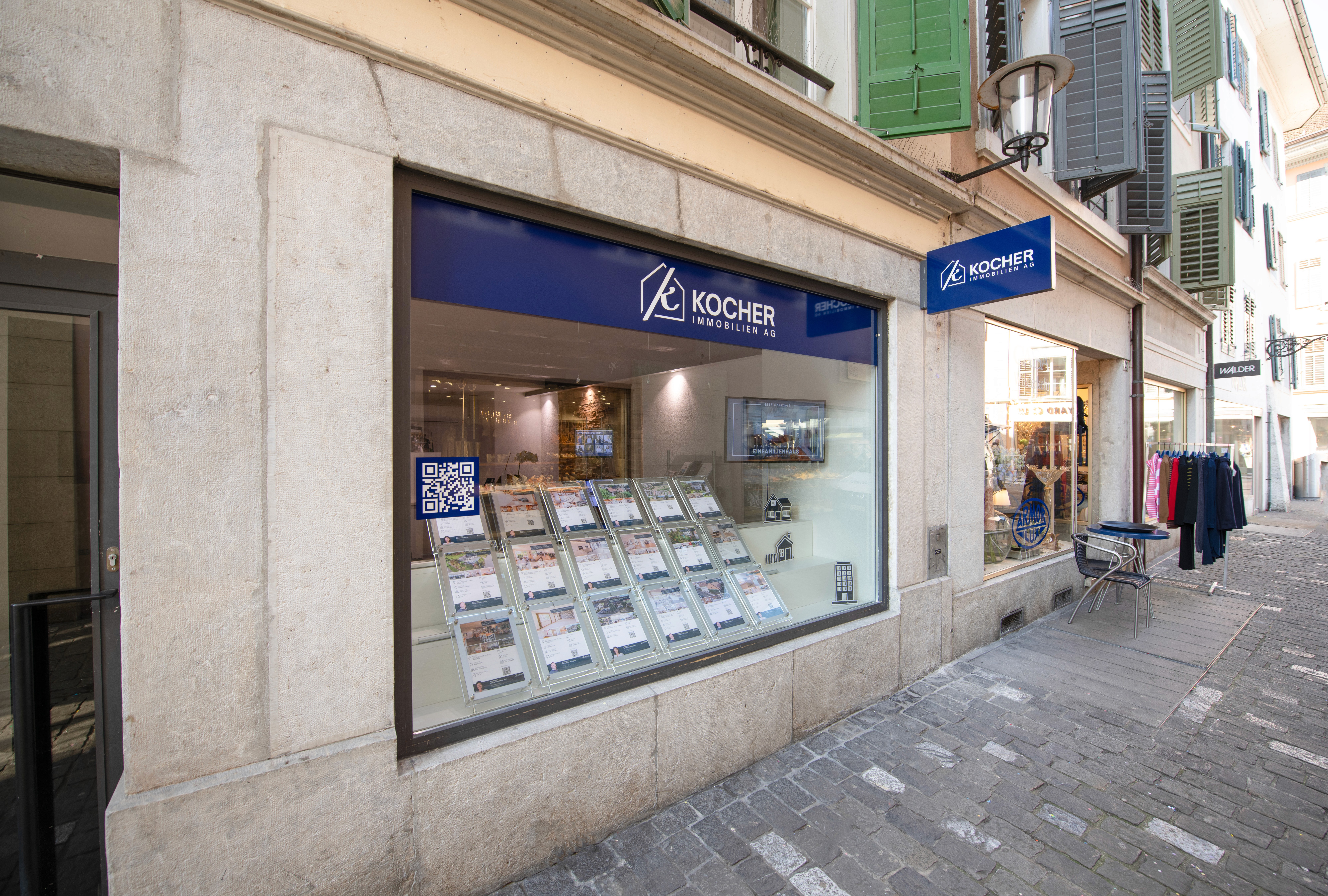 Gesamtes Team von Kocher Immobilien sitzt gemeinsam im Büro und lacht in moderner Umgebung