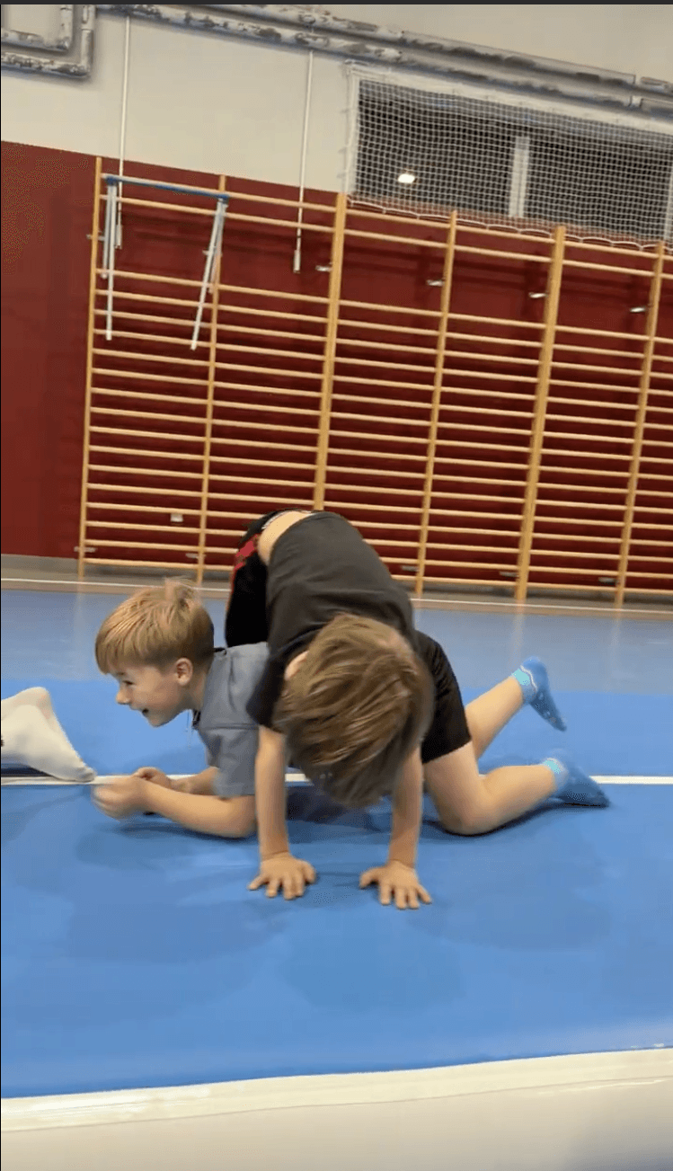 Skupiony chłopczyk przechodzi pod tunelem uczniów w podporze przodem