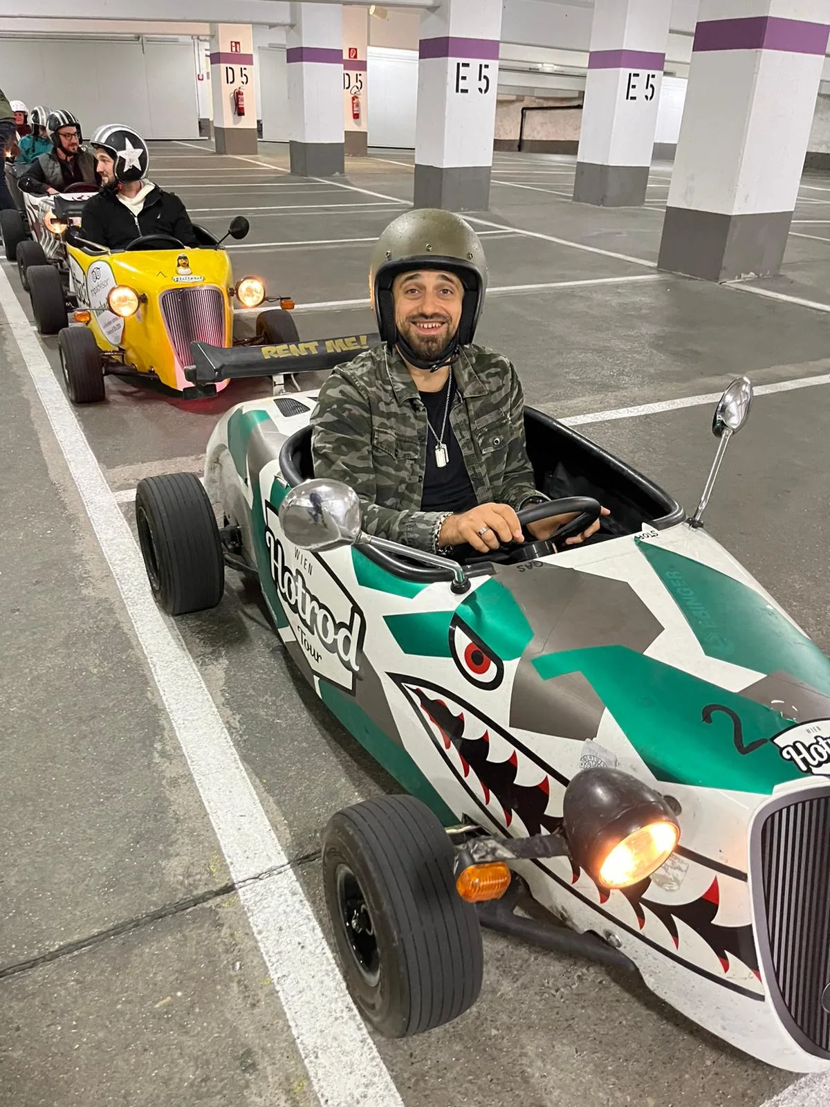 Team in Gokarts mit Helmen in einer Parkgarage vor dem Start