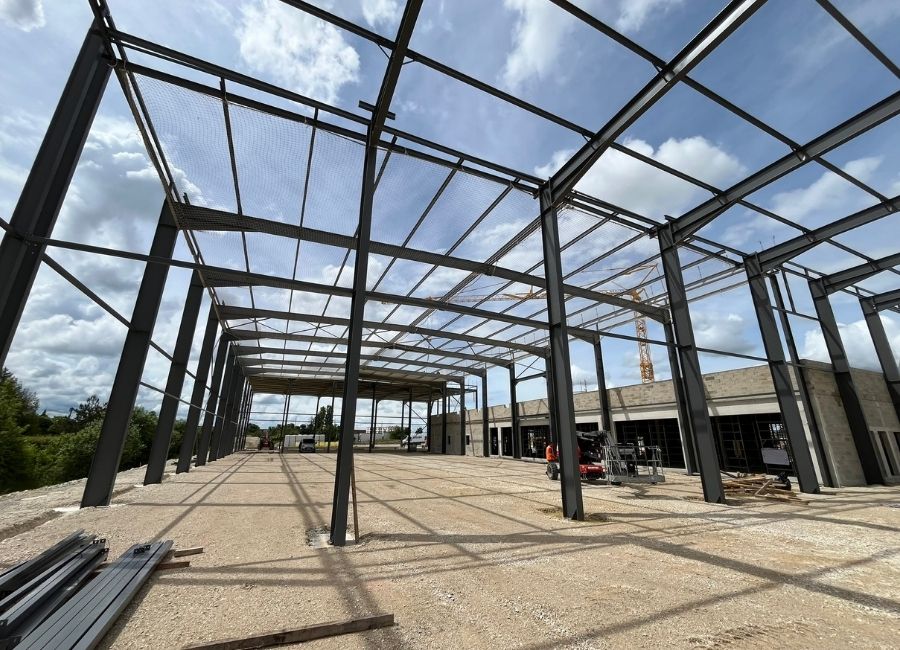Vue diagonale d’une charpente métallique noire en cours de pose sur chantier.