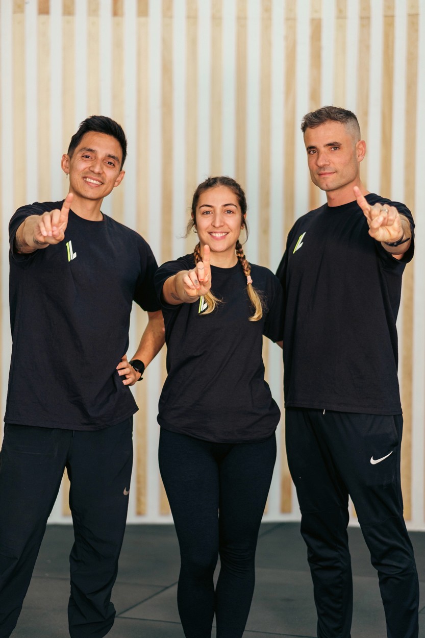 Entrenadors de One Life Training posant amb el somriure i fent equip al gimnàs funcional de Gràcia, Barcelona.