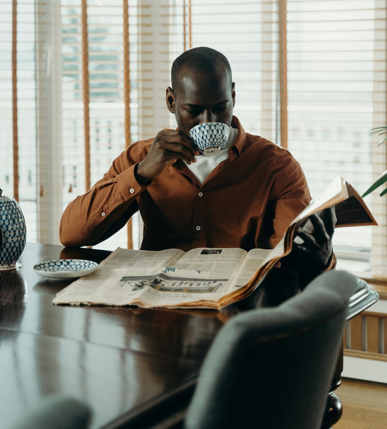 man drinks coffee and reads newspaper
