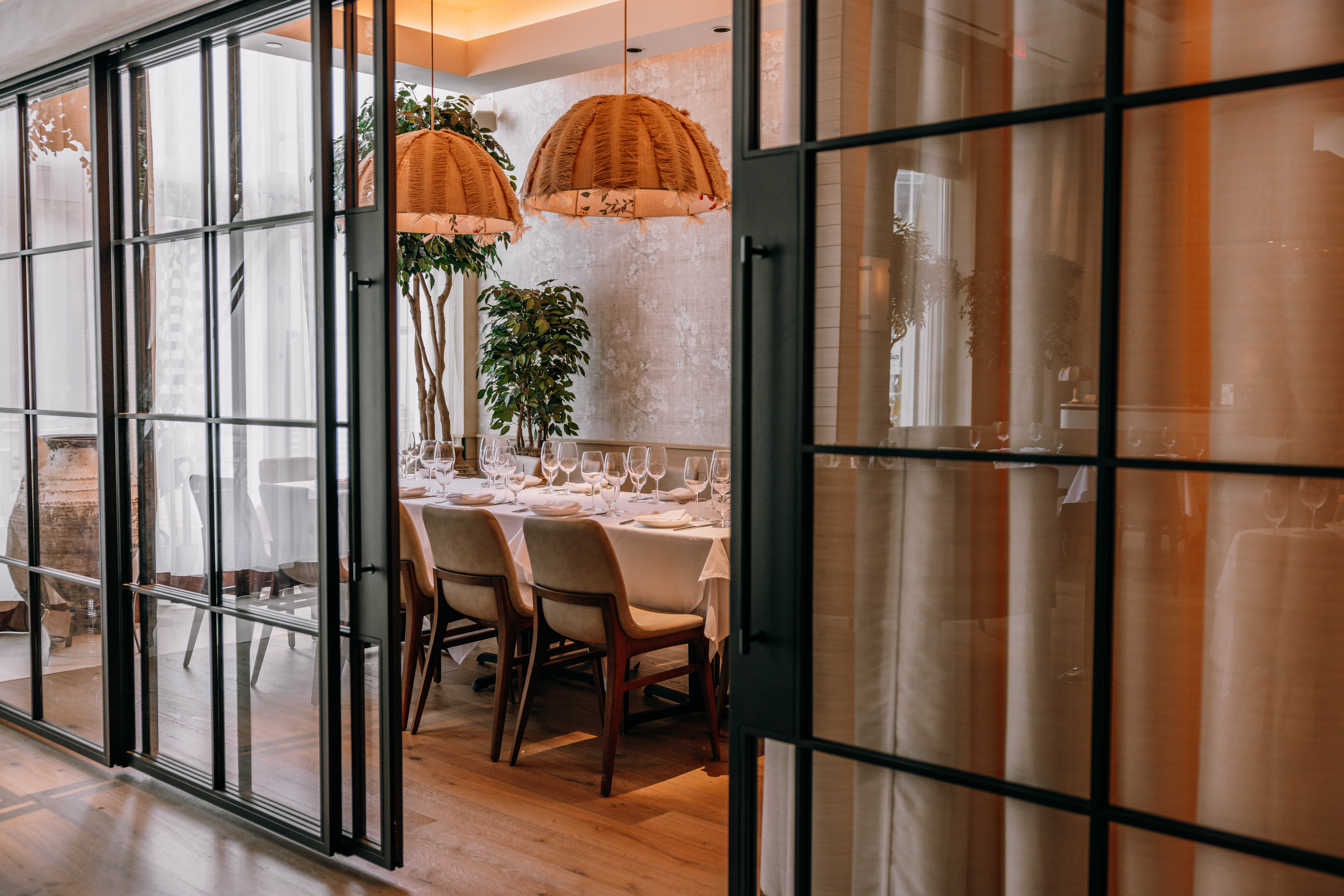 A view through glass doors into a modern conference room with a large table and stylish chairs.
