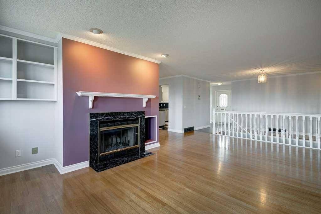 Strathcona open living area before: purple fireplace wall, built-in shelving and honey oak floors