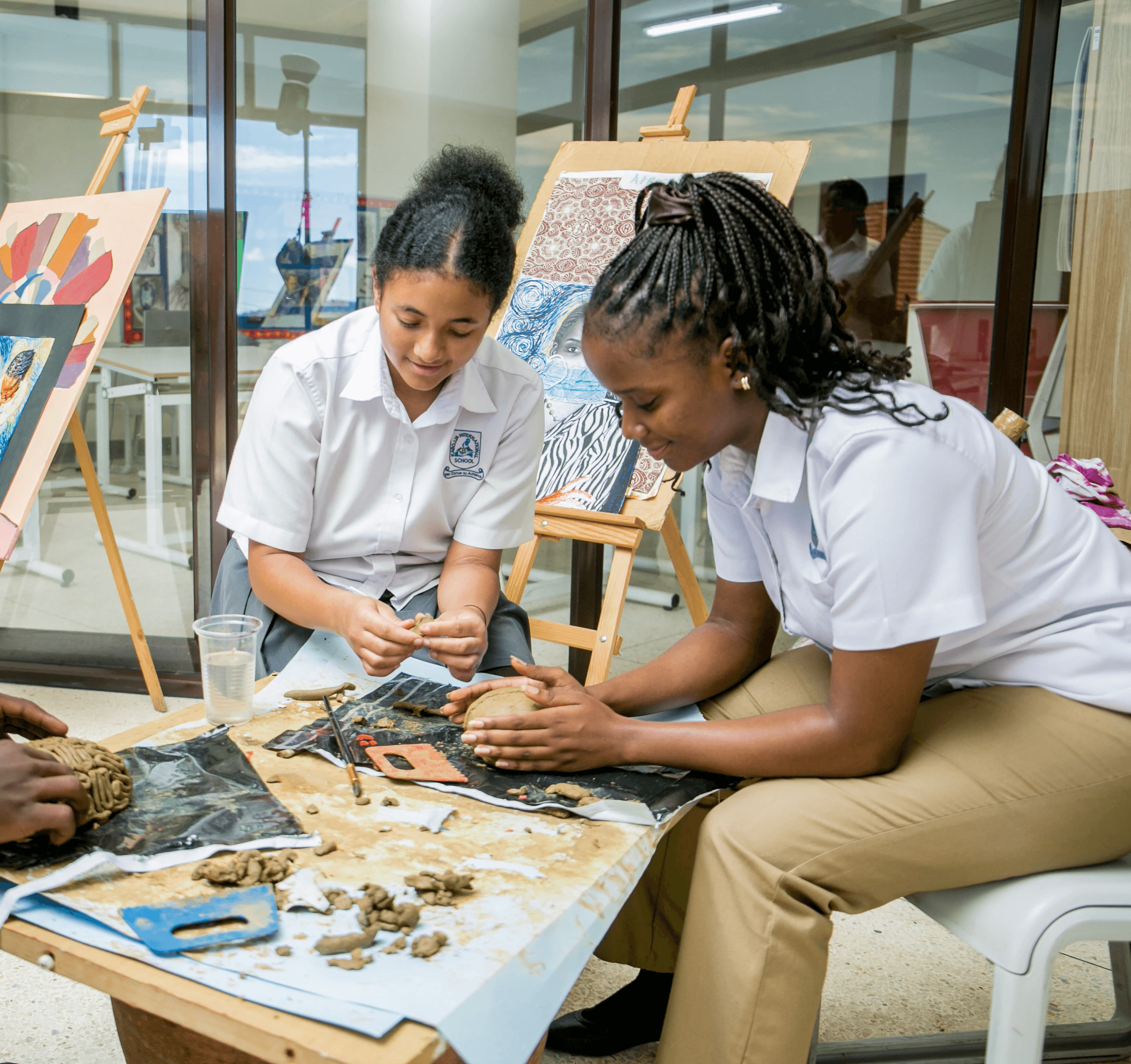 A student wearing a red uniform sits while holding a book in his hands