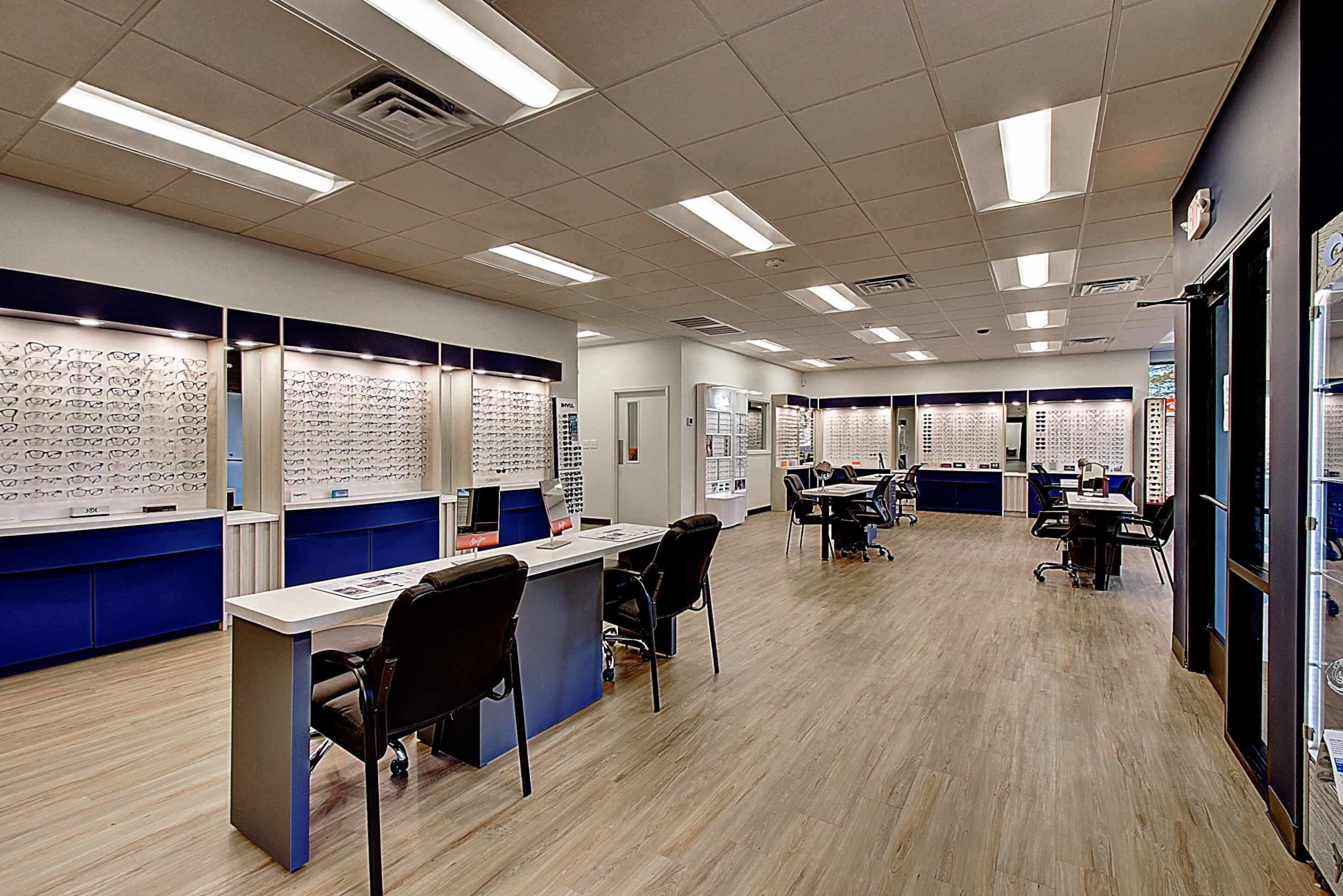 Modern office interior featuring desks, chairs, and retail displays against a light-colored wall.