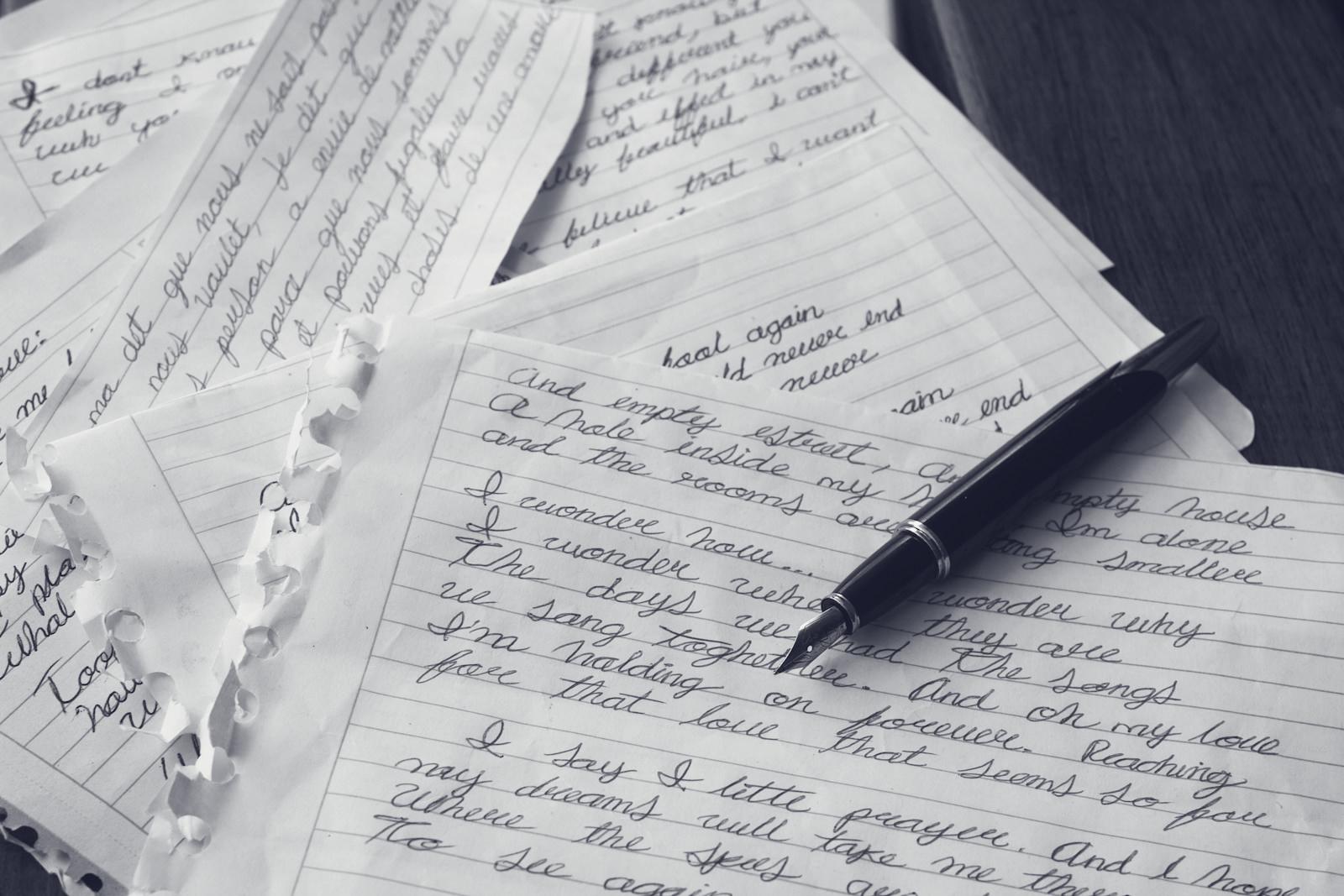 A pen resting on handwritten pages