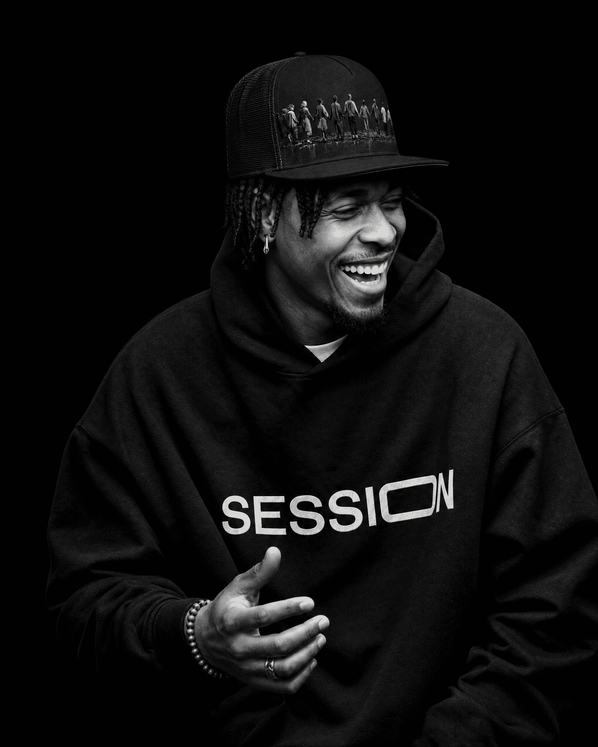Man laughing in a black Session Zone community-graphic cap and black SESSION logo hoodie.