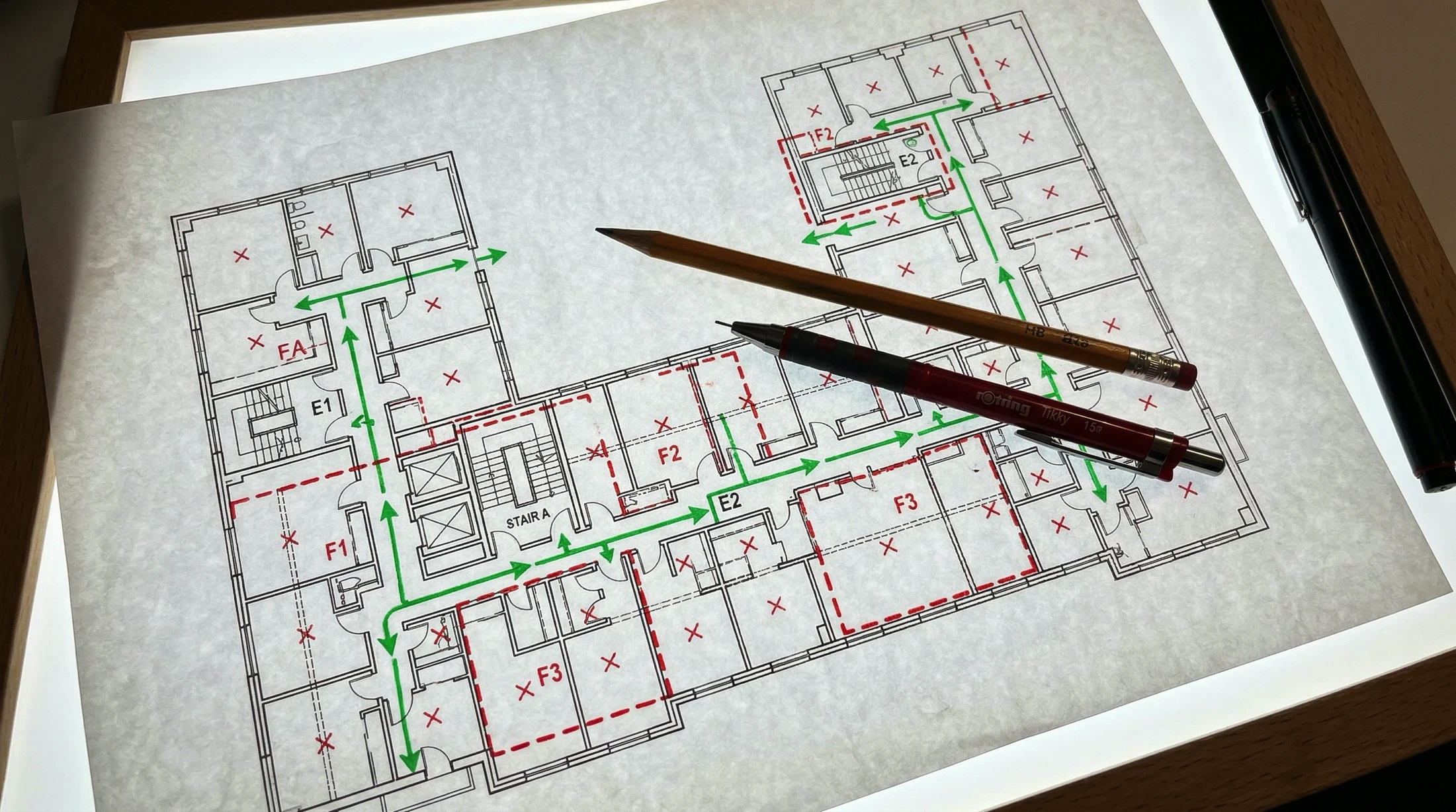 Floor plan with green arrows indicating a path, 2 pencils, red Xs, and red dashed lines.
