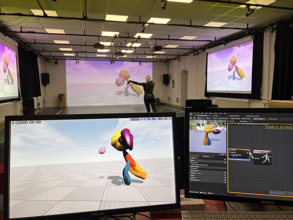 A women wearing a motion capture suit in studio assisting an intern