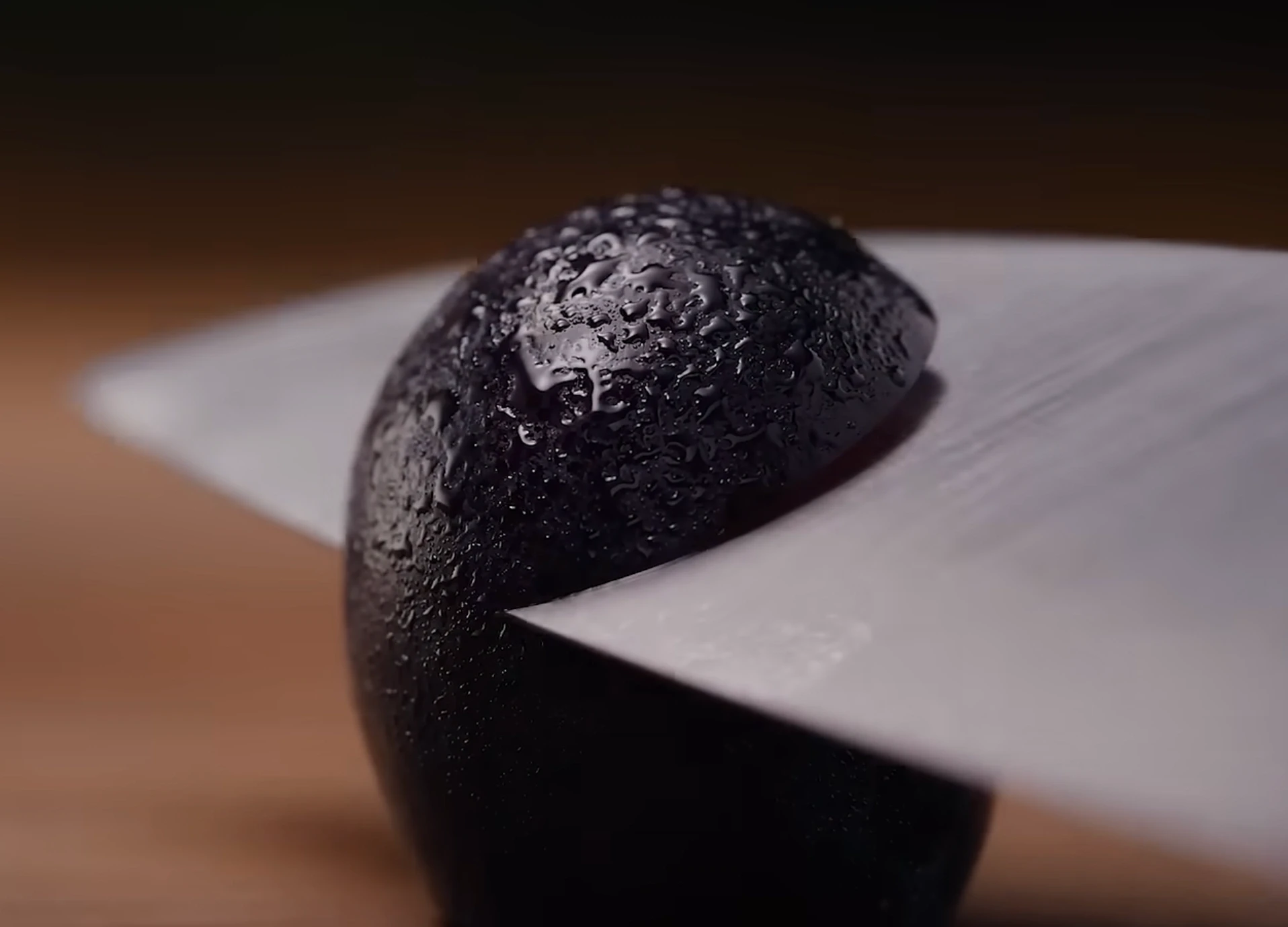 Testing the final sharpness of a knife by slicing through a grape effortlessly after stropping.