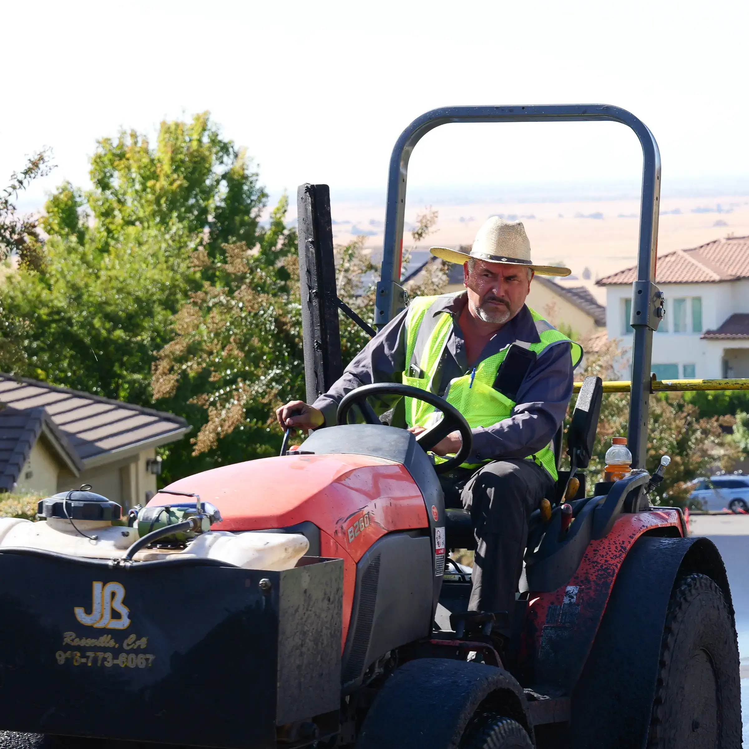 Closeup photo of construction worker on seal coat squeegee tractor