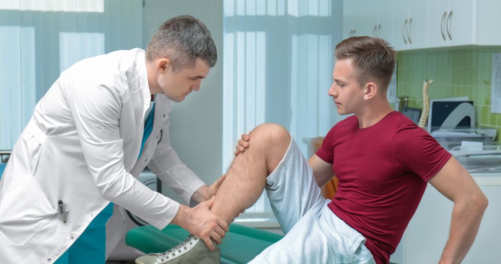 Chiropractor examining a patient's leg in a clinic