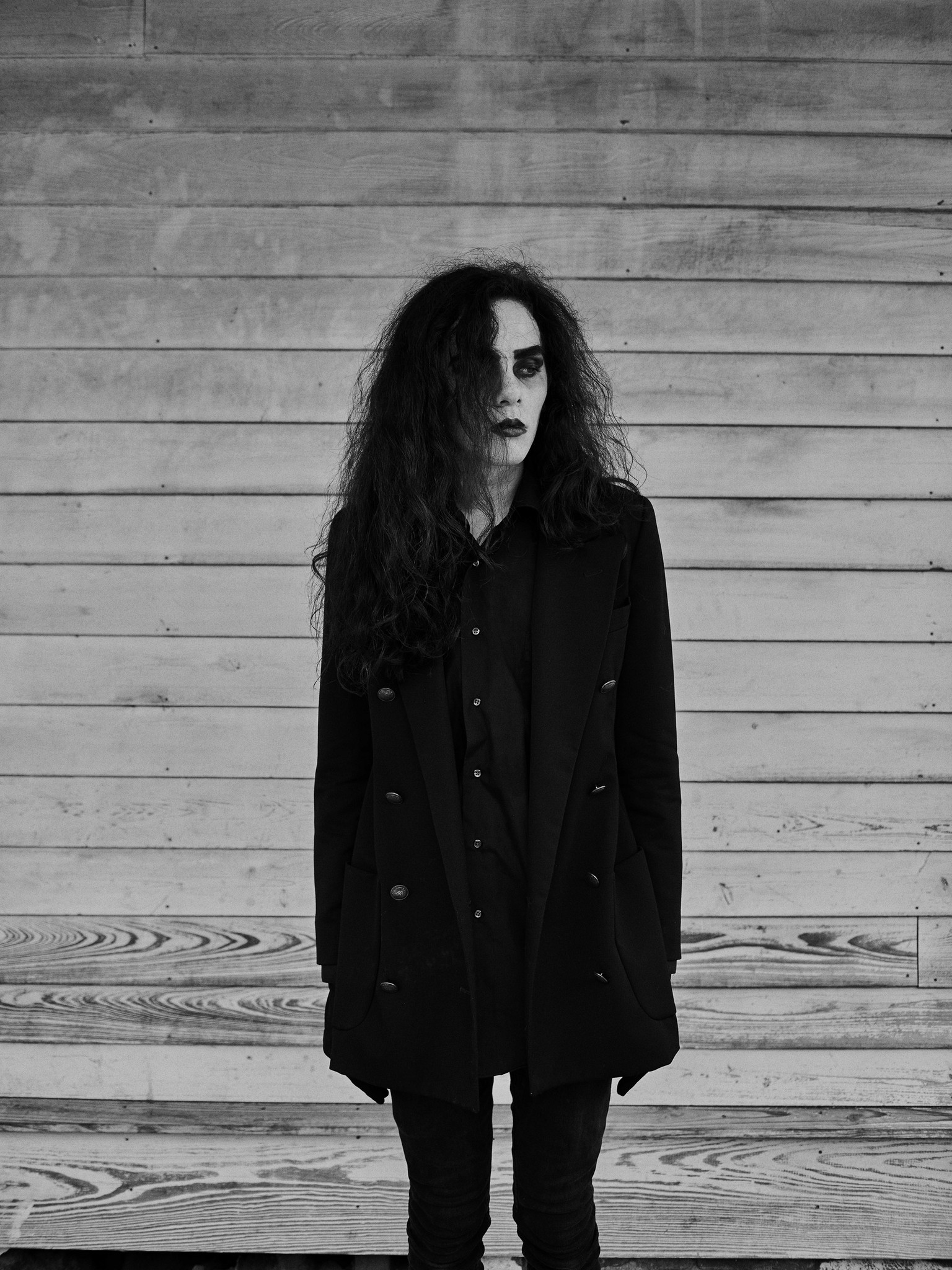 Black and white photograph of a goth, alternative young person, wearing heavy makeup. Shot in New Orleans, Louisiana as part of the personal project NOLA Freak Punks by British photographer Craig Mulcahy. 
