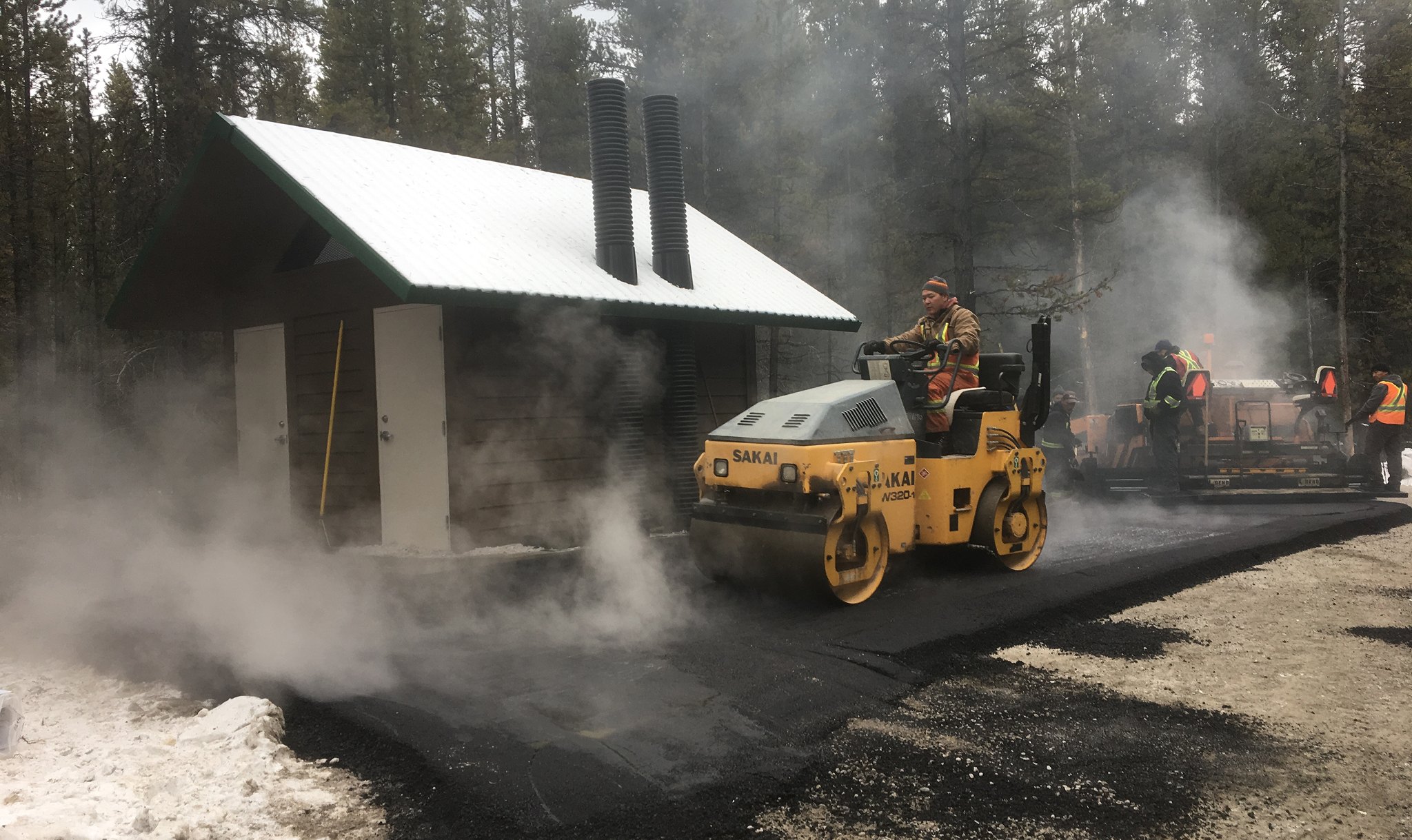Asphalt compaction at Boulton Creek Campground with construction crew working near facilities building