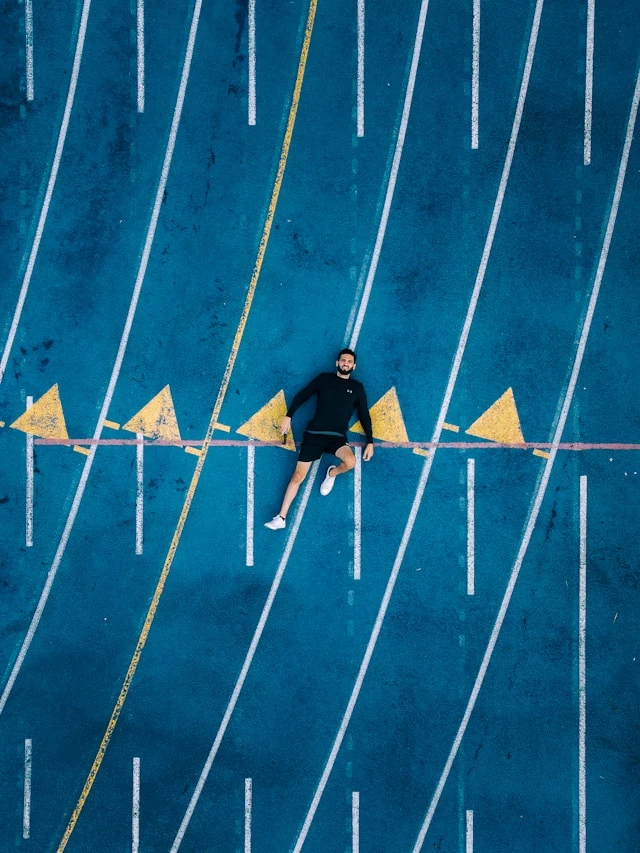Person lying on a blue outdoor track