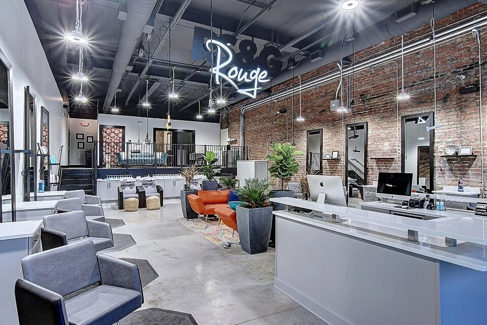 Modern open salon space featuring stylish furniture, plants, and a bright, welcoming atmosphere.