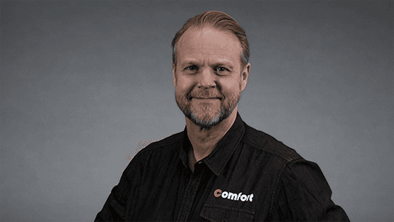 Geir Lunde markedssjef Comfort i sort skjorte med Comfort logo foran nøytral grå bakgrunn