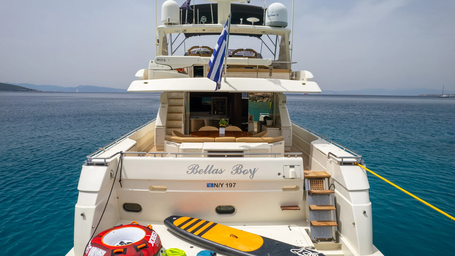 White Rock 36 speedboat with captain at helm cruising calm blue waters near Paros coastline with hills in background.