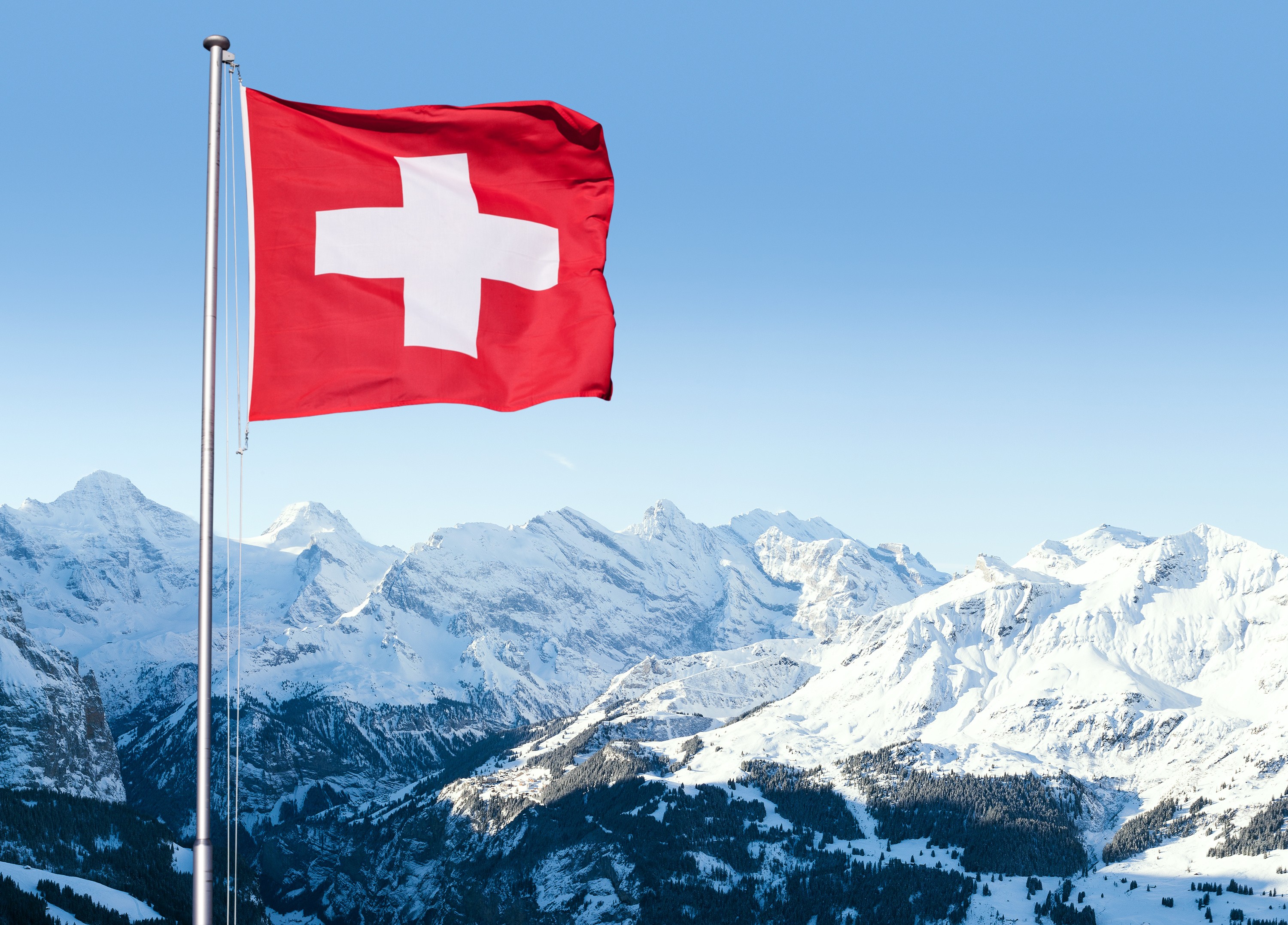 Swiss flag flying above the Alps
