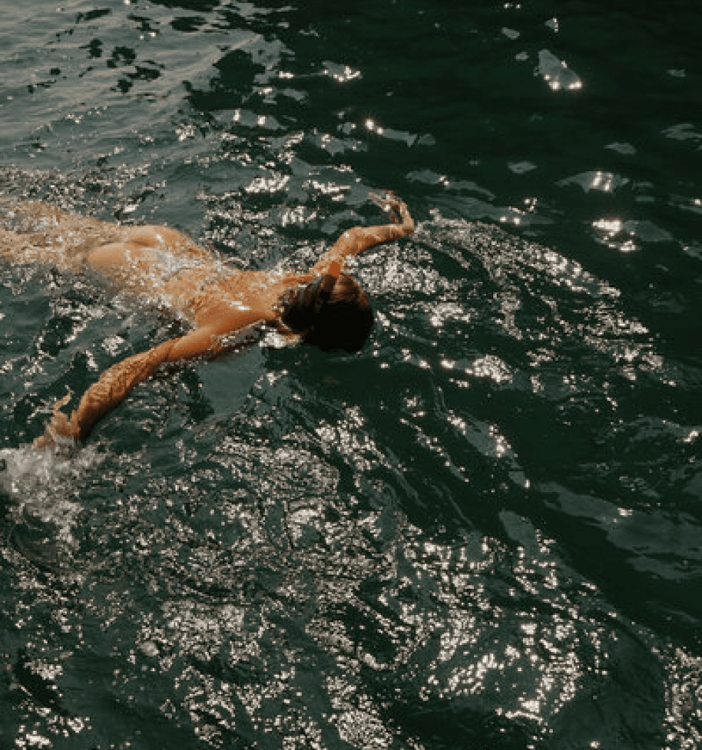 woman snorkeling with arms wide in dark green water