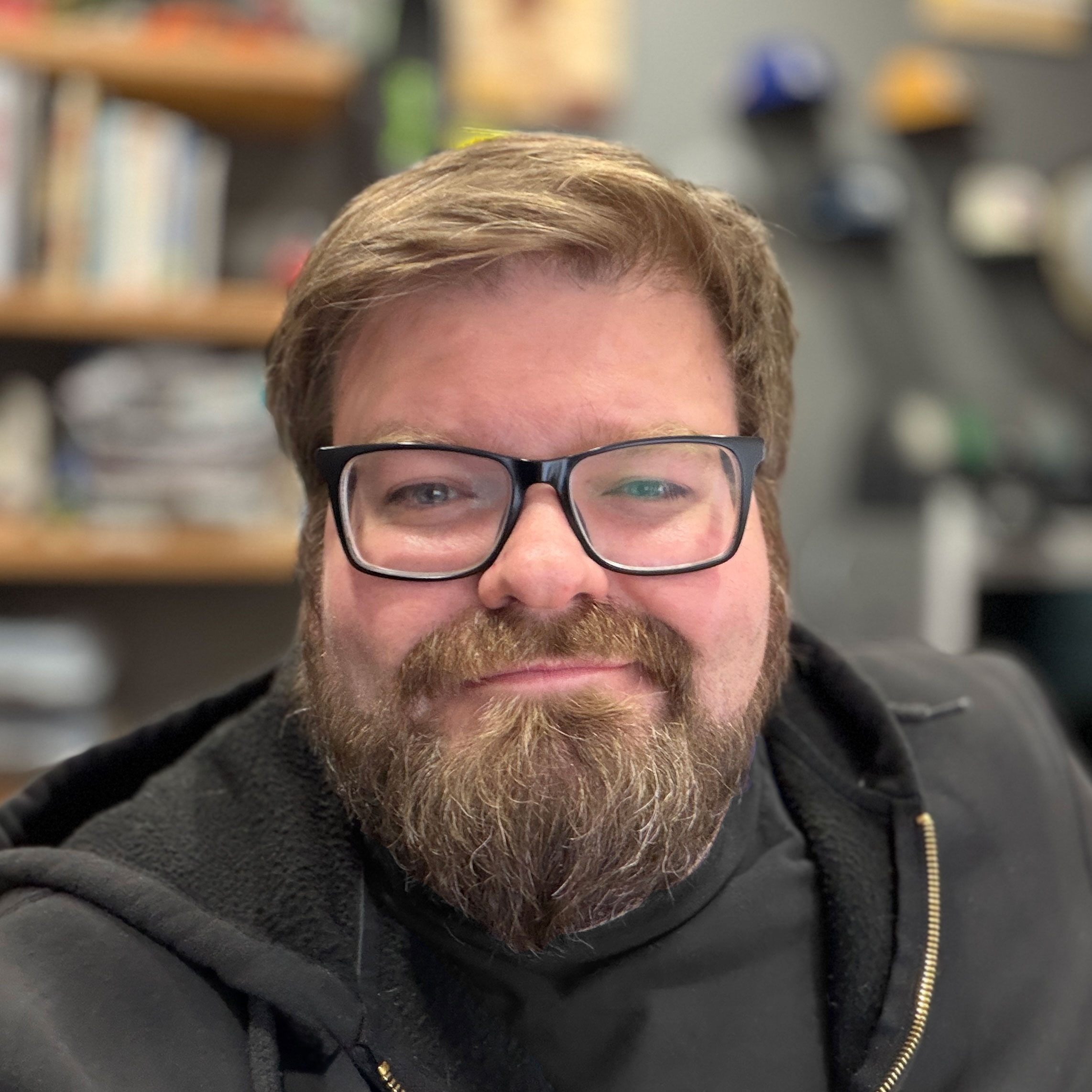 Portrait of Brian Talbot- He has black framed glasses and a short beard.