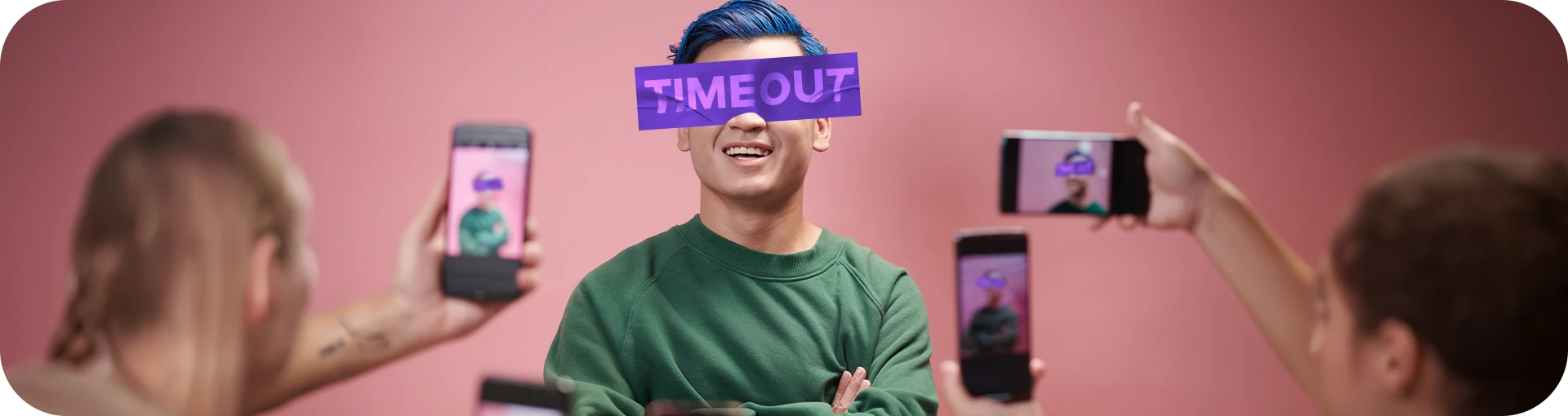 Pessoas estão tirando uma foto de um modelo sorridente, que posa com uma faixa em seus olhos escrito "time out"