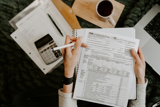 Person reviewing documents with calculator and laptop, illustrating the tax documents