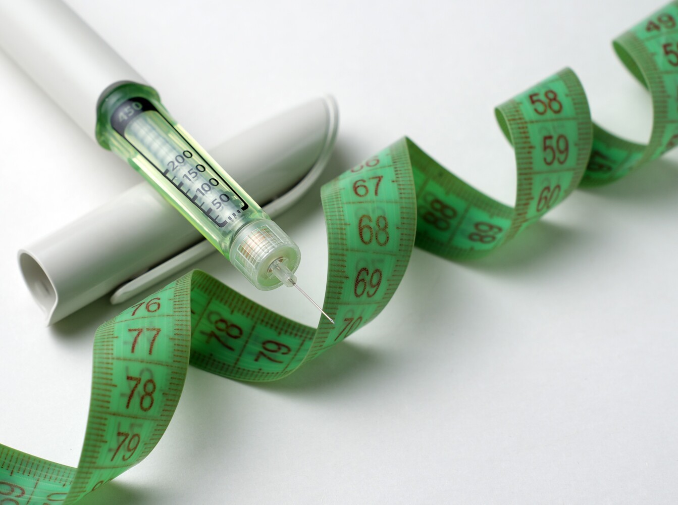 weight loss FDA-approved injection pen on a surface with a tape measure