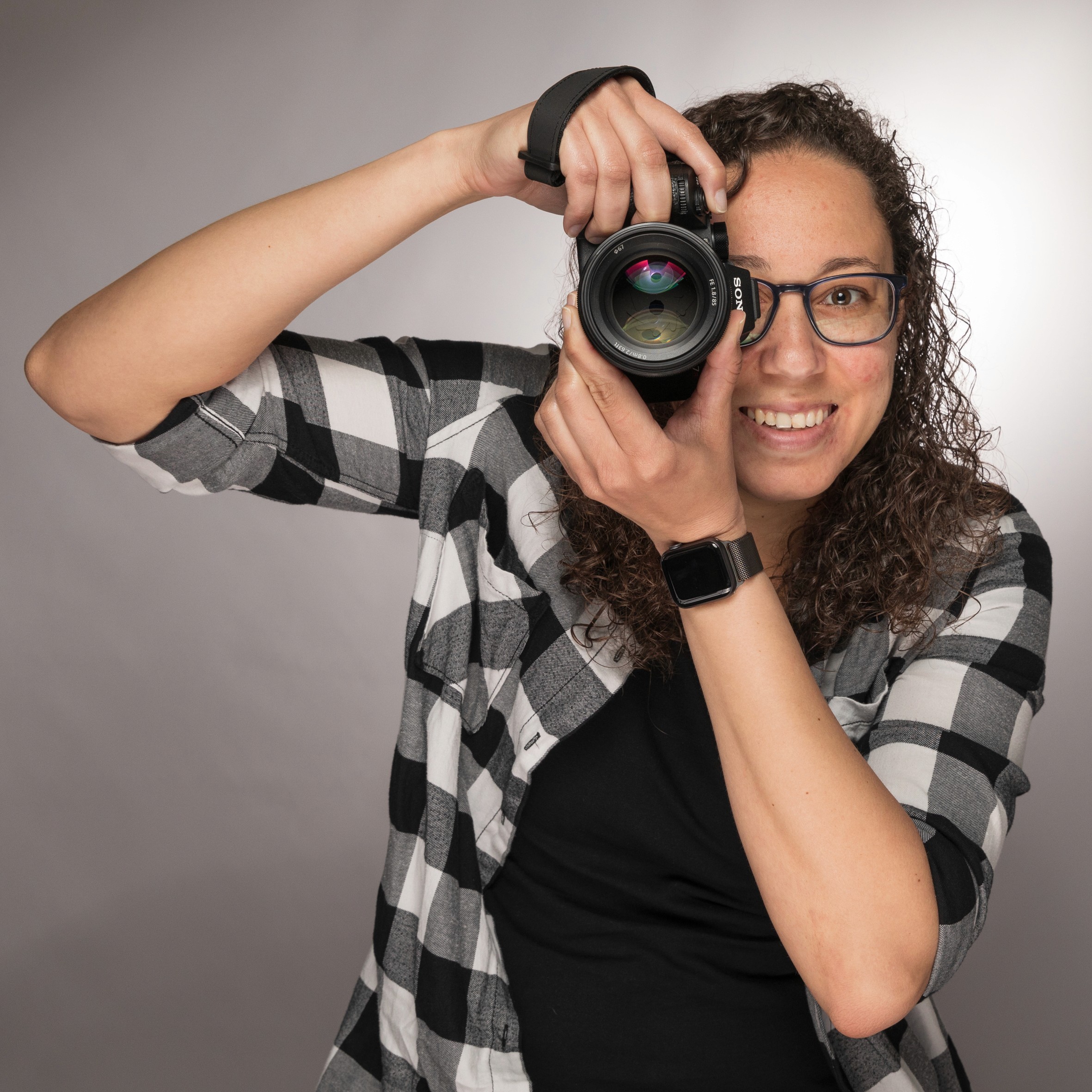 A person with shoulder-length blonde hair wearing a black newsboy cap and a black sweater.