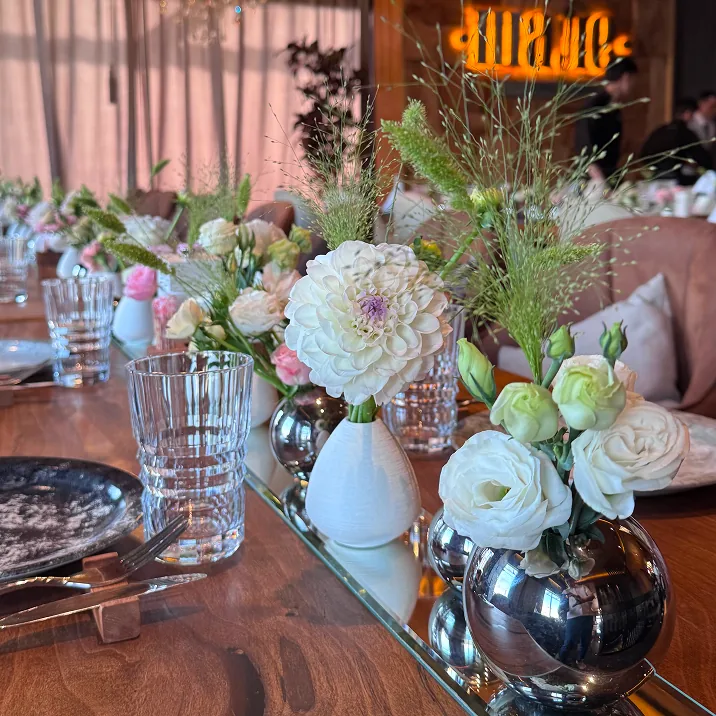 Decorated event table with floral arrangements, marbled plates, and warm ambient lighting