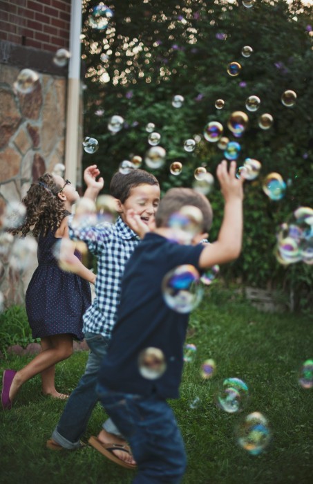 Children playing outdoors with bubbles, reflecting positive emotional wellbeing and childhood development