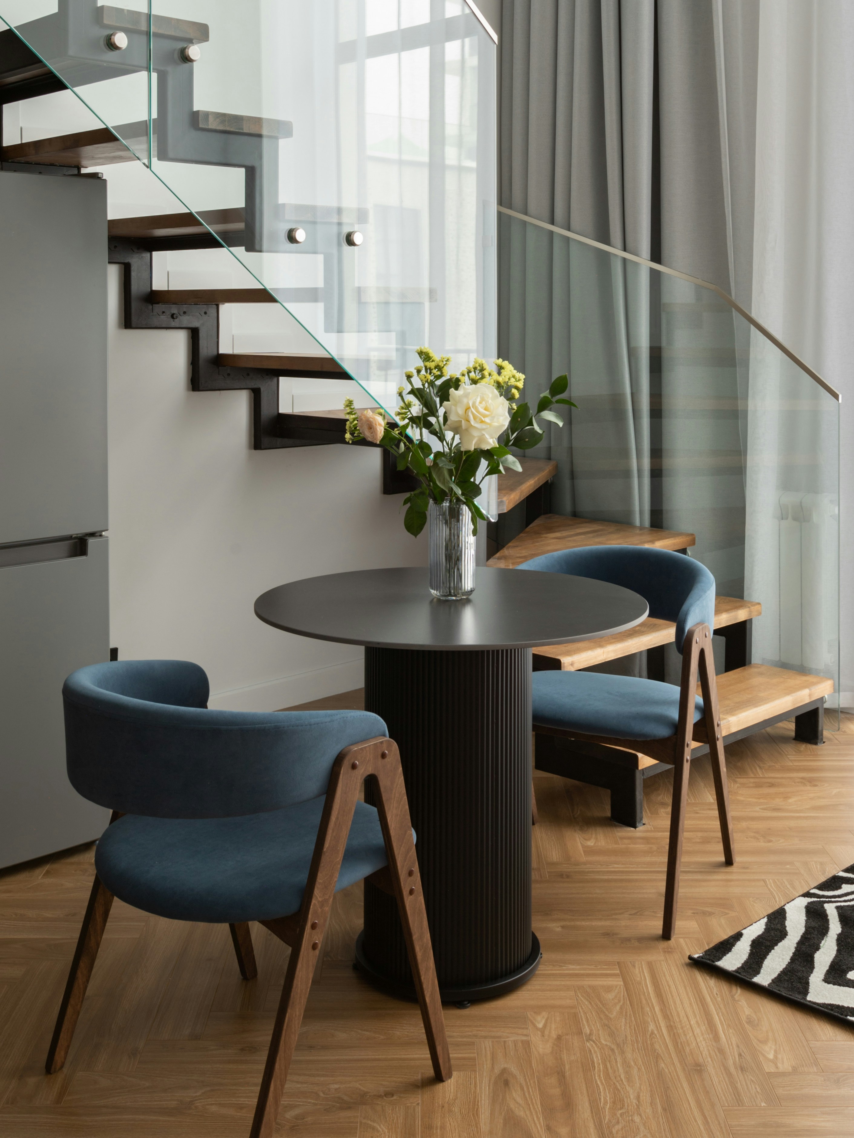 Two blue chairs at a round table with flowers.