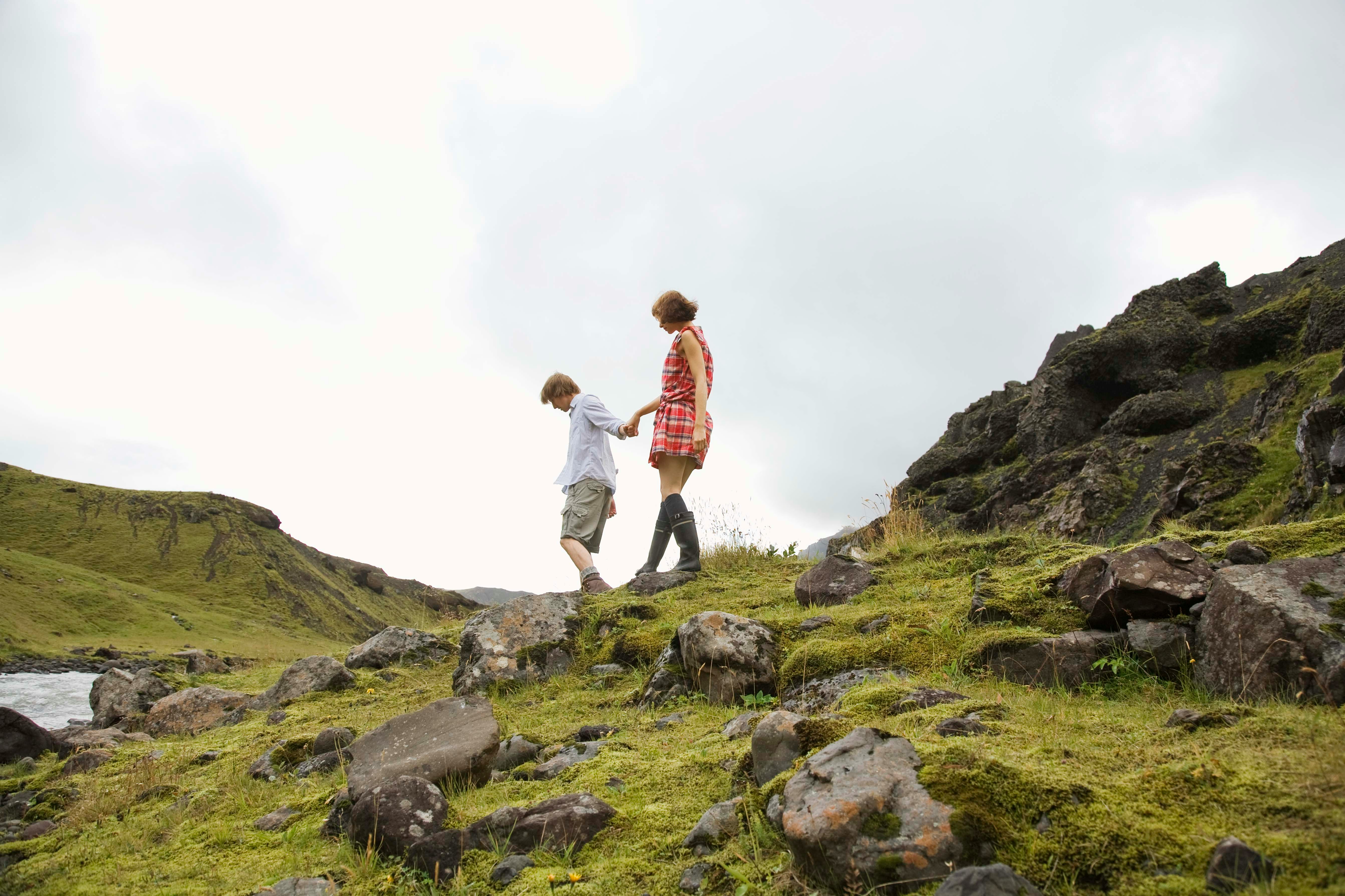 A couple walking across a mossy volcanic landscape in Iceland.