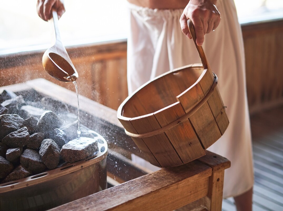 man heating coals in a sauna to lose weight alongside his wellness routine