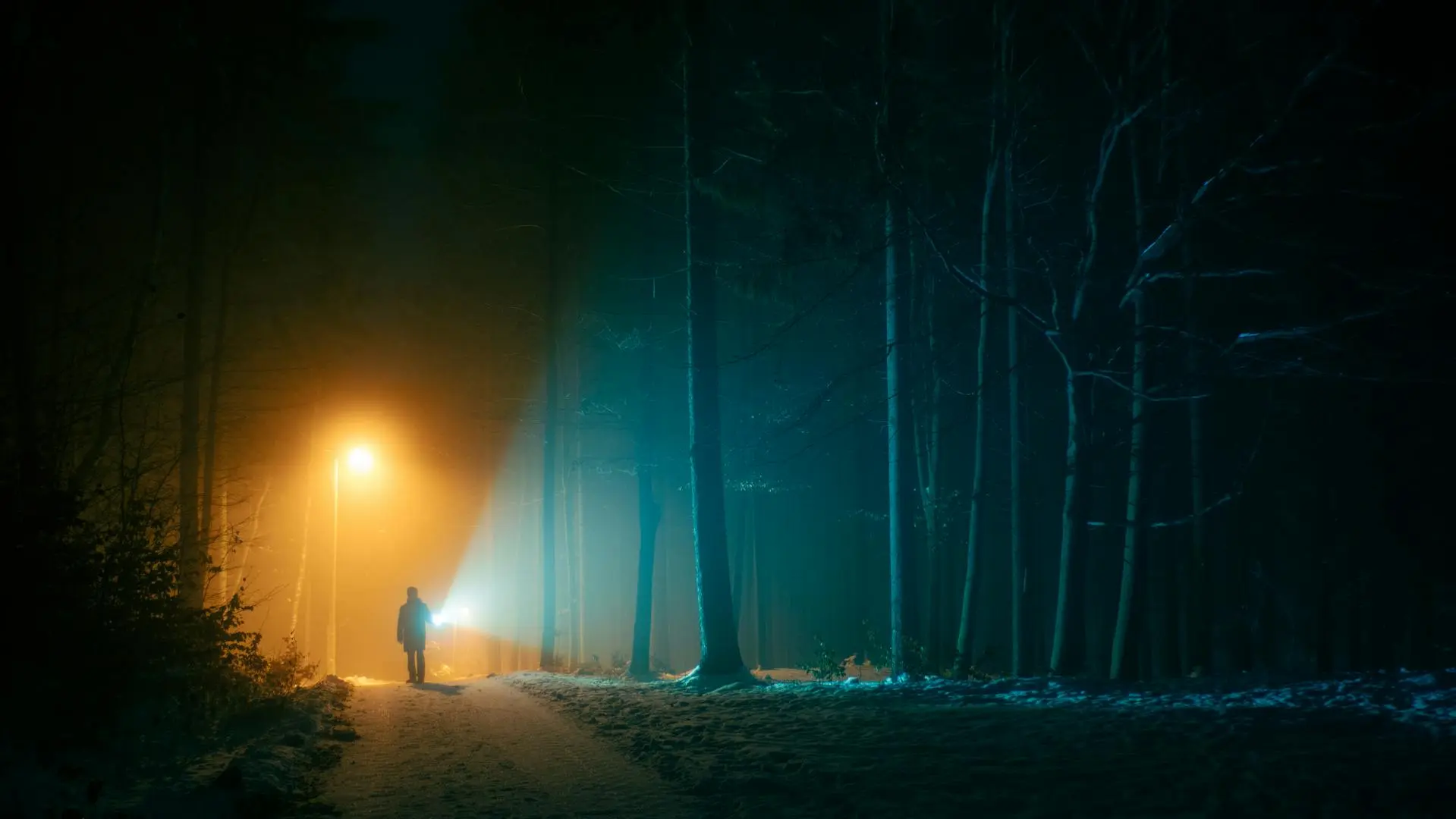 Man walking alone in the dark with a flashlight