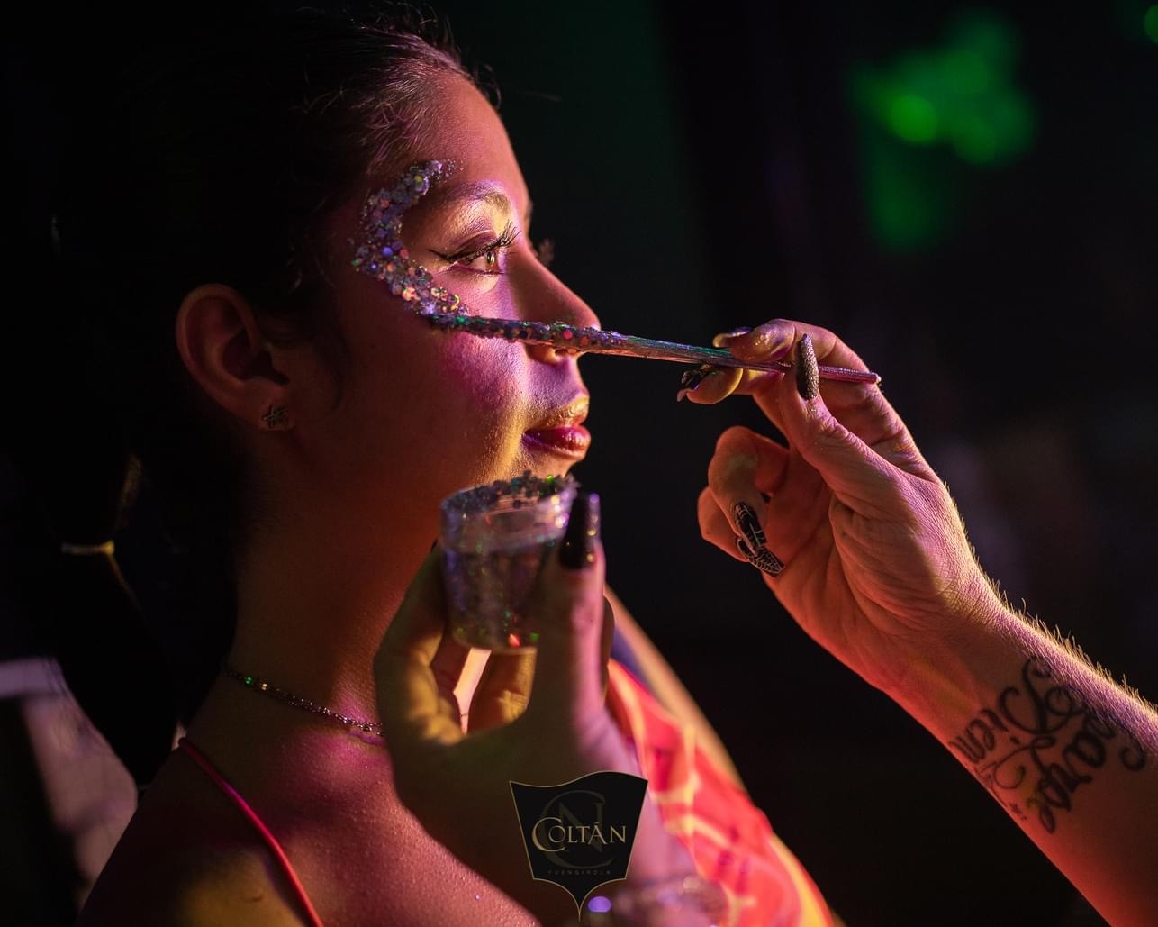 Vibrant digital illustration of a cat with blue eyes, featuring splashes of multicolored paint in yellow, blue, and pink on a dark background, showcasing a creative and artistic style.